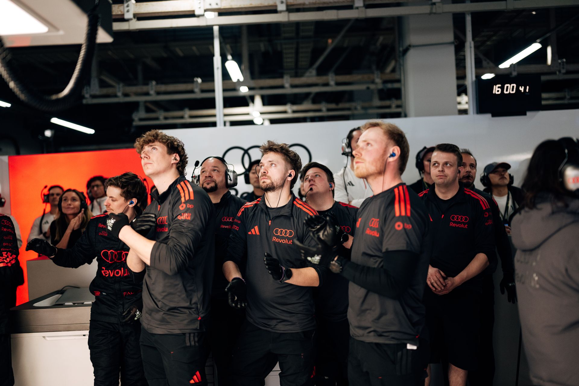 A larger group of Audi Revolut F1® Team crew members watch the session unfold on the garage screens.
