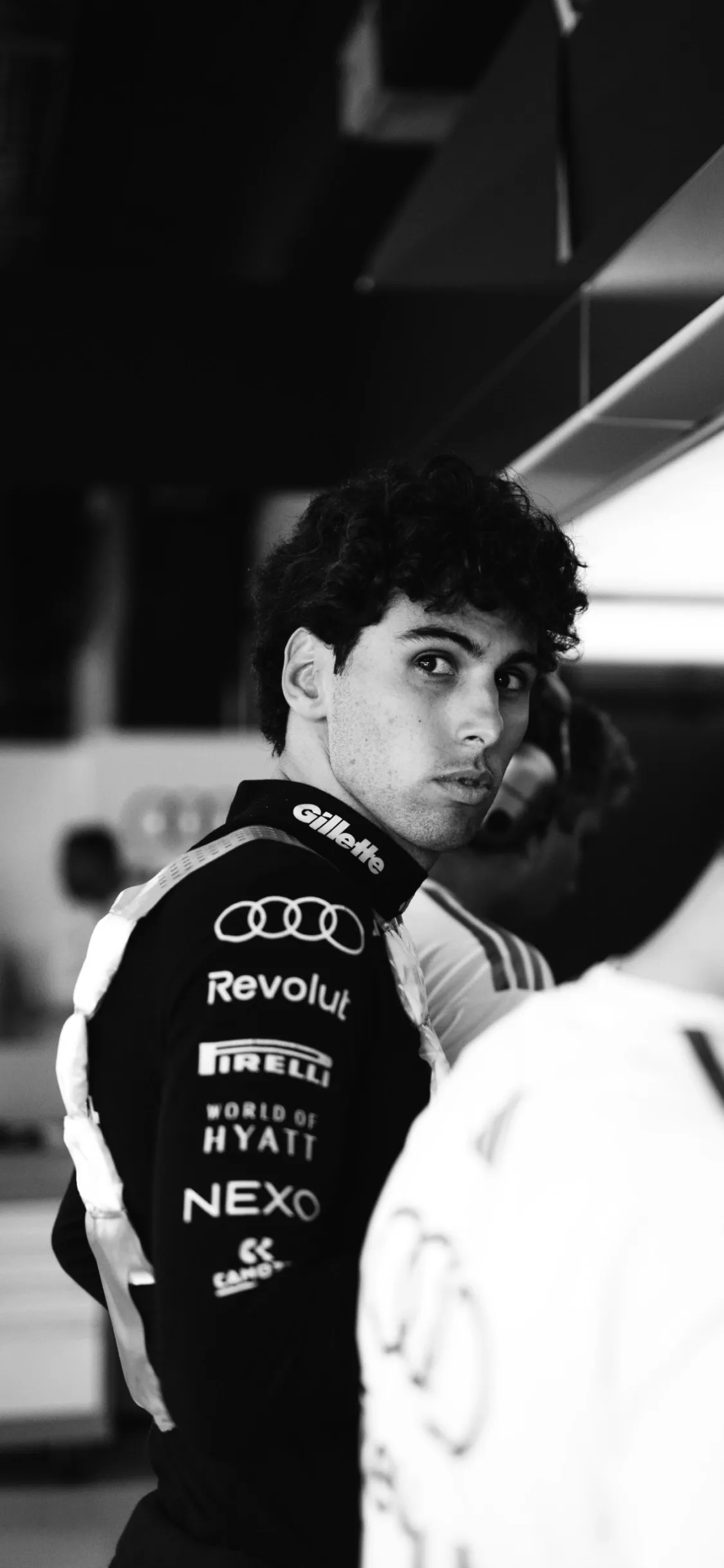 Portrait of Gabriel Bortoleto in branded gear looking over his shoulder inside the paddock, showcasing identity and culture of the Audi Revolut F1® Team