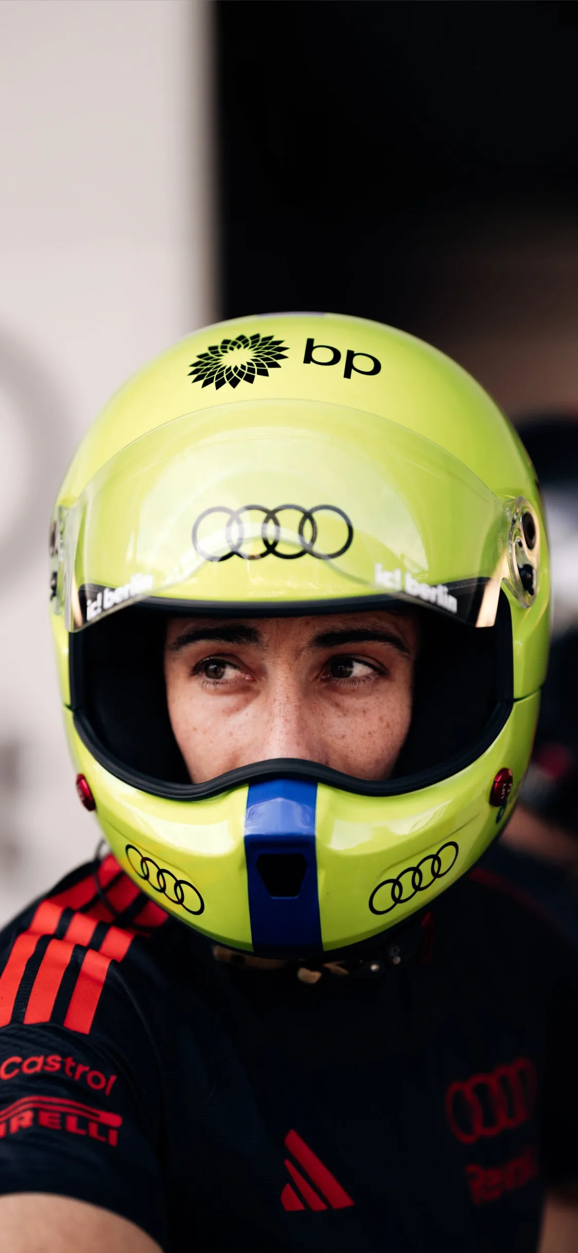 Close-up portrait of pitstop crew member waering a bright yellow helmet with Audi branding, representing precision and focus within the Audi Revolut F1® Team