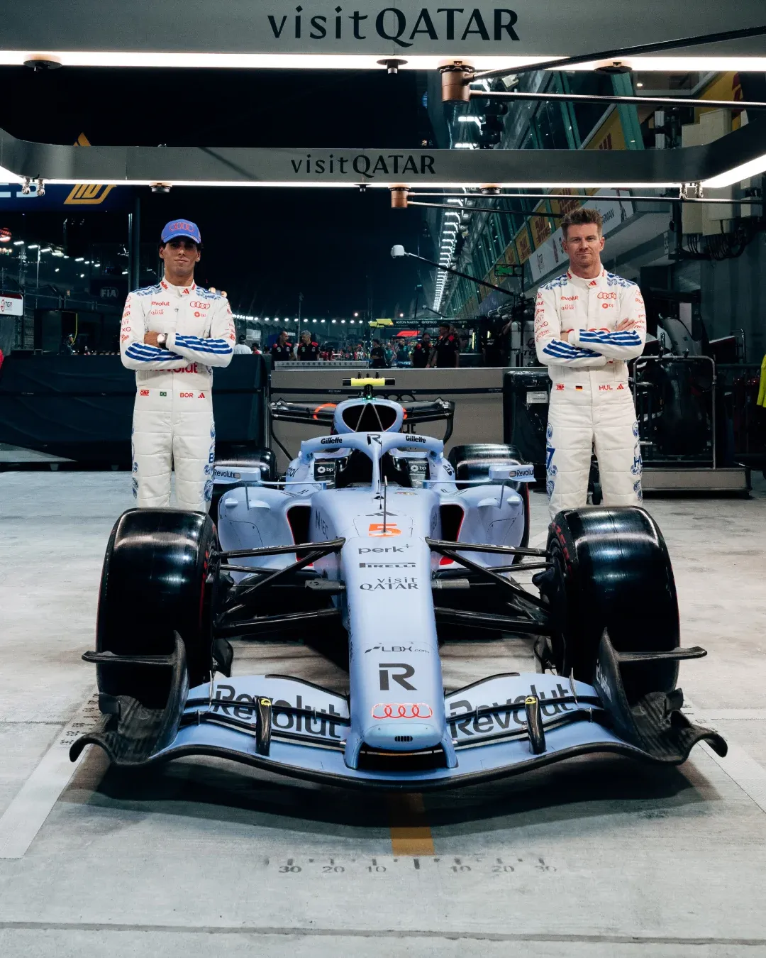 Audi Revolut F1® Team drivers Gabriel Bortoleto and Nico Hulkenberg pose with the F1 car in the Singapore GP garage