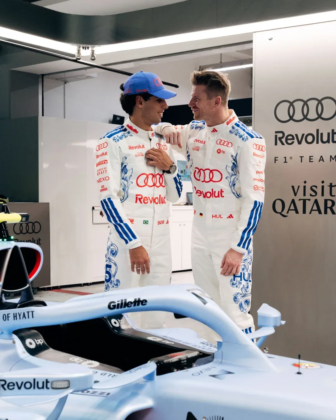 Audi Revolut F1® Team drivers Gabriel Bortoleto and Nico Hulkenberg talk beside the F1 car in the Singapore GP garage