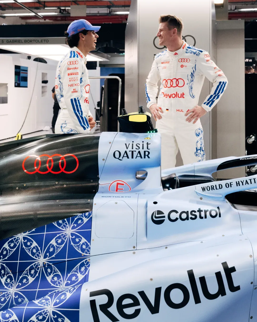 Audi Revolut F1® Team drivers Gabriel Bortoleto and Nico Hulkenberg beside the F1 car in the Singapore GP garage
