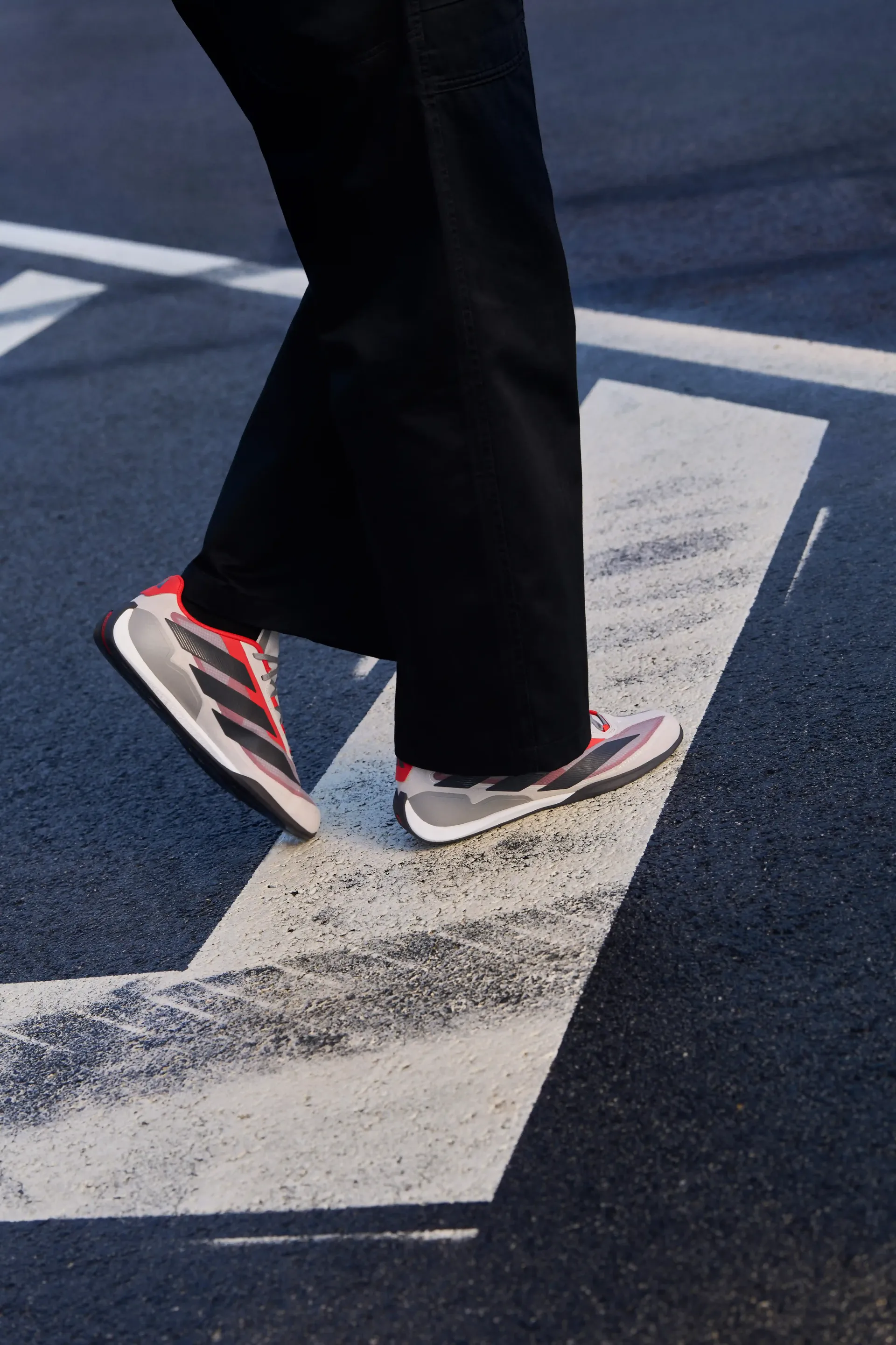 Close up of running, Adidas, Formel 1 Revolut Audi F1, Teamwear, shoes in motion on marked asphalt surface focus on dynamics performance and sporty lifestyle
