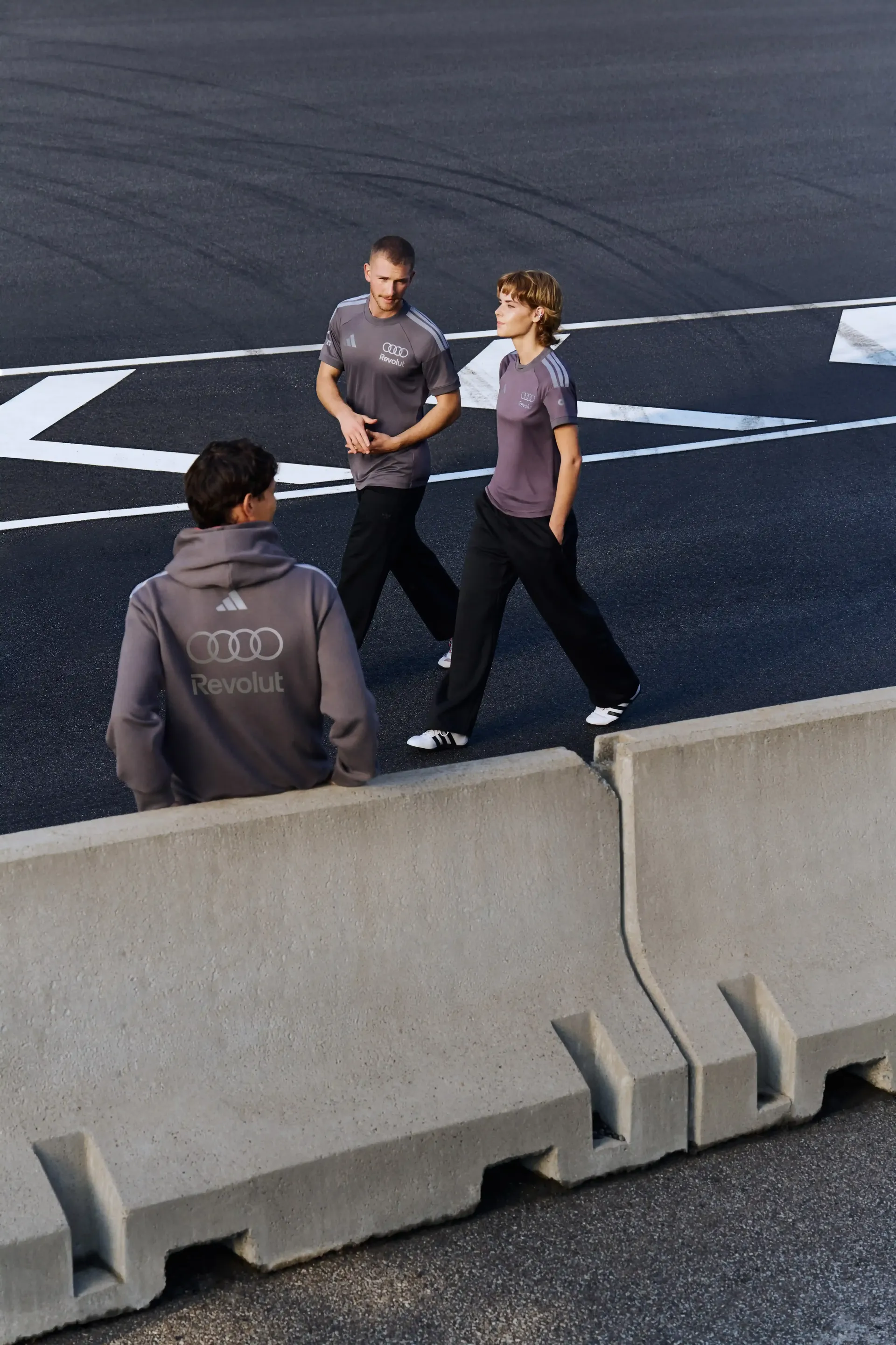 Group of models in grey teamwear on urban asphalt area top-down view modern motorsport-inspired streetwear setting