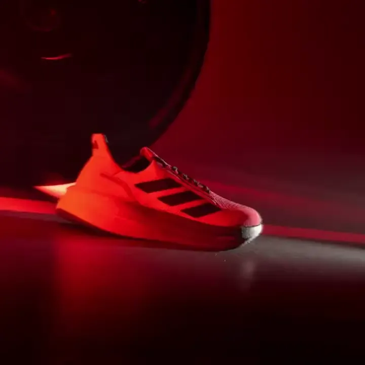 Close-up of a red Adidas sneaker three dark stripes red background tire motorsport