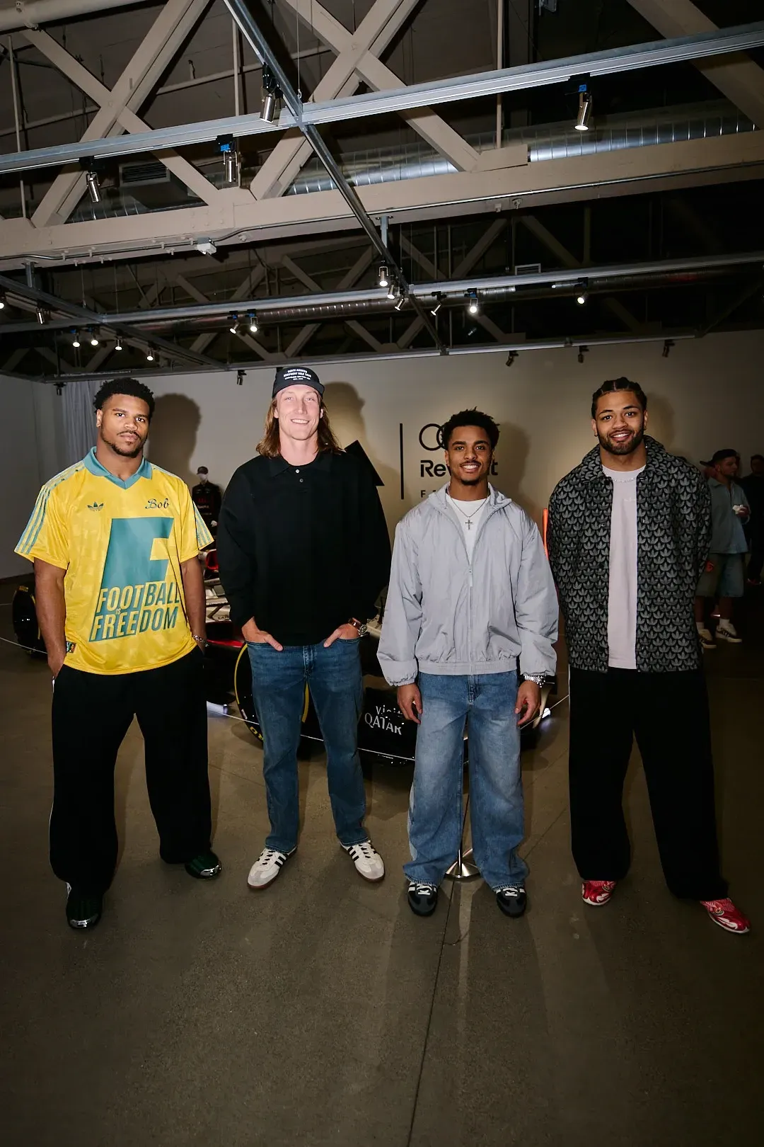 Four event attendees pose for a group photo in front of the show car in the exhibition space.