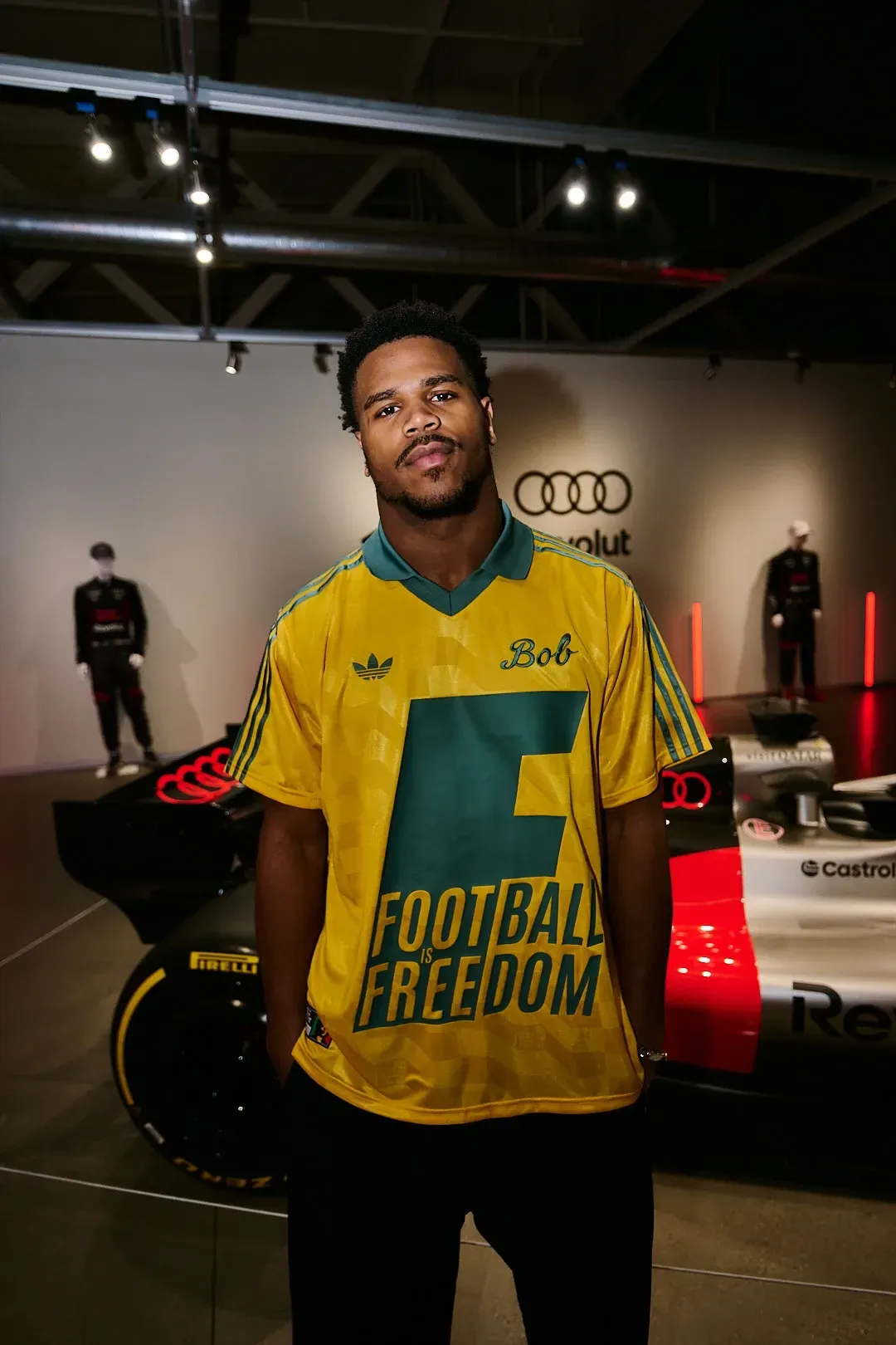 Portrait of an event attendee in a yellow Adidas jersey standing in front of the show car.