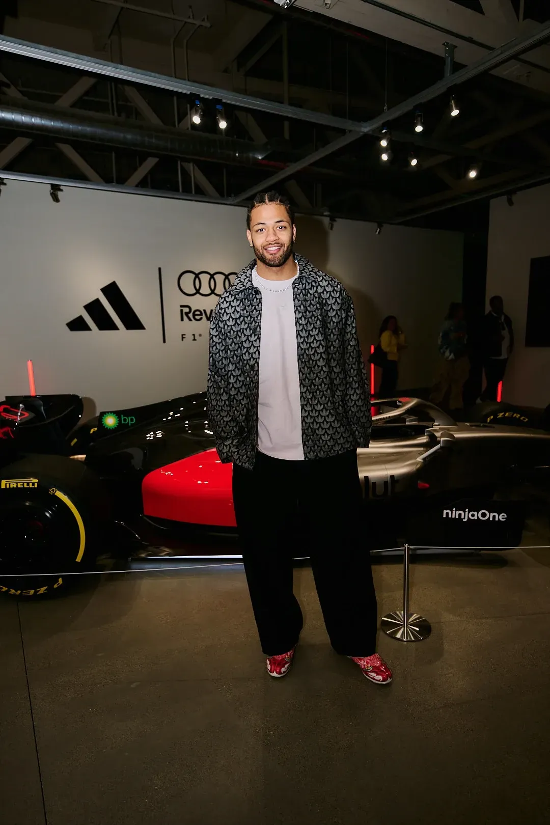 Portrait of an event attendee wearing a patterned jacket standing in front of the show car.
