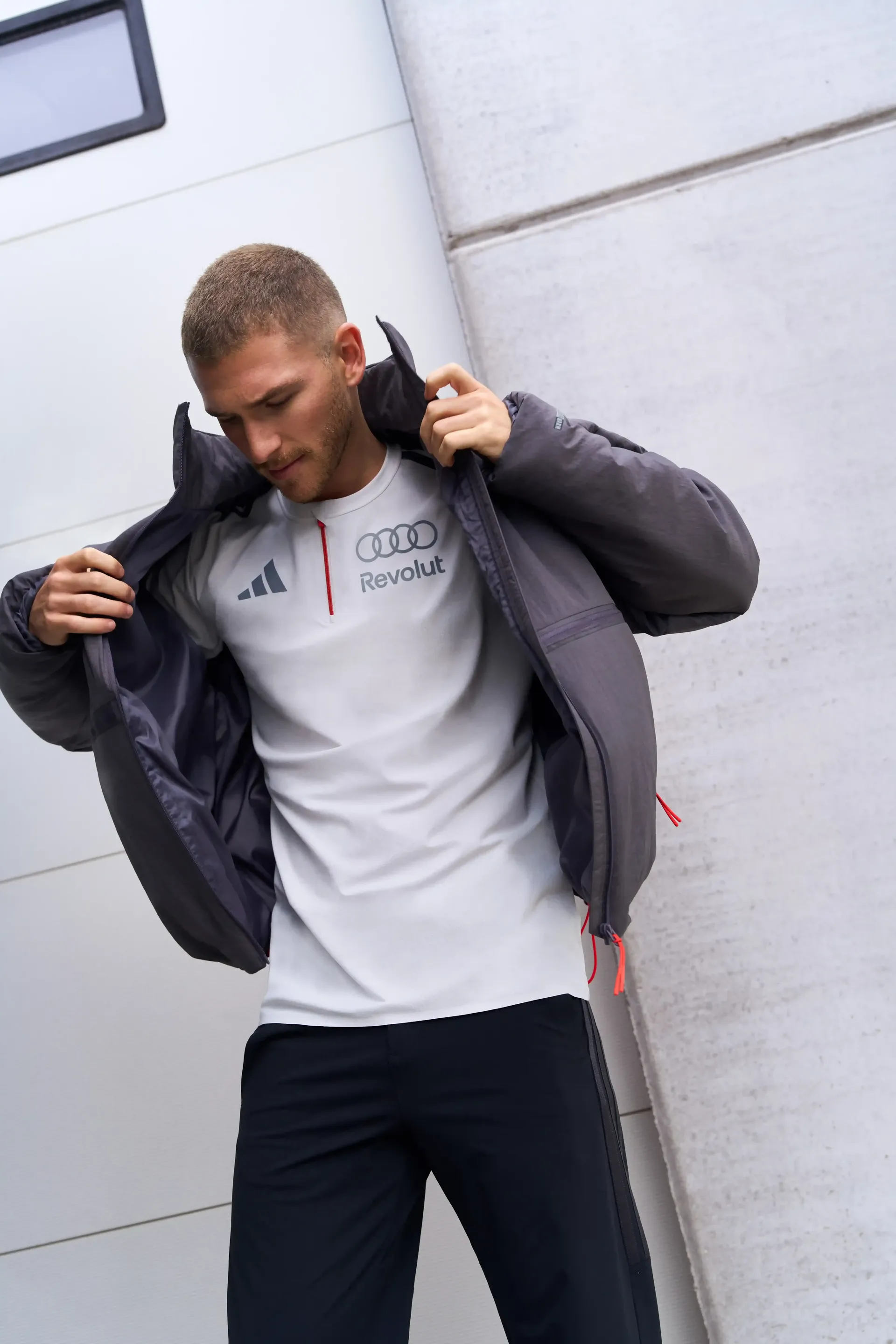 Model putting on dark jacket white shirt underneath sporty elegant pose modern architecture background