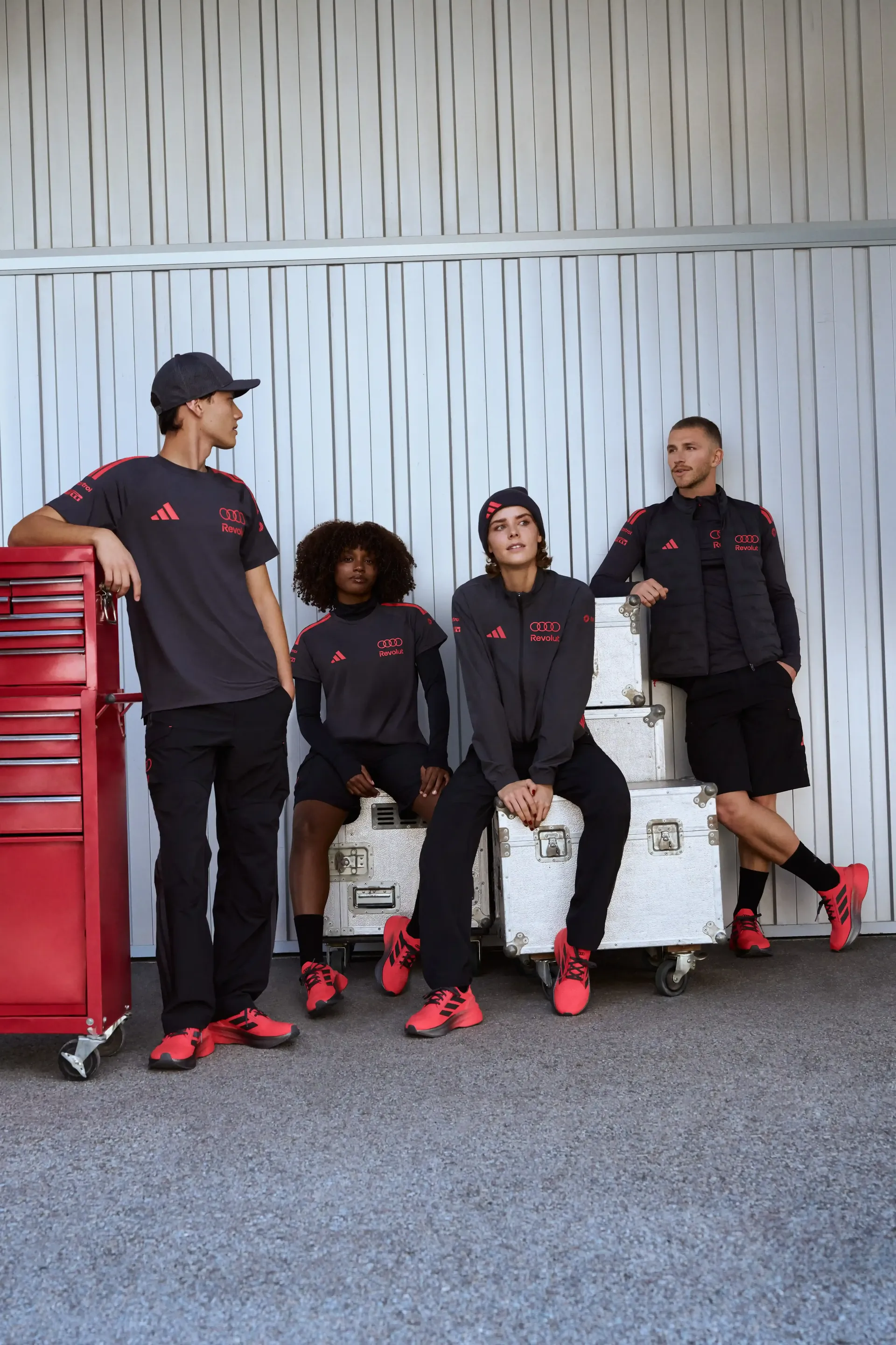 Group of models in dark teamwear sitting and standing industrial background strong team dynamics