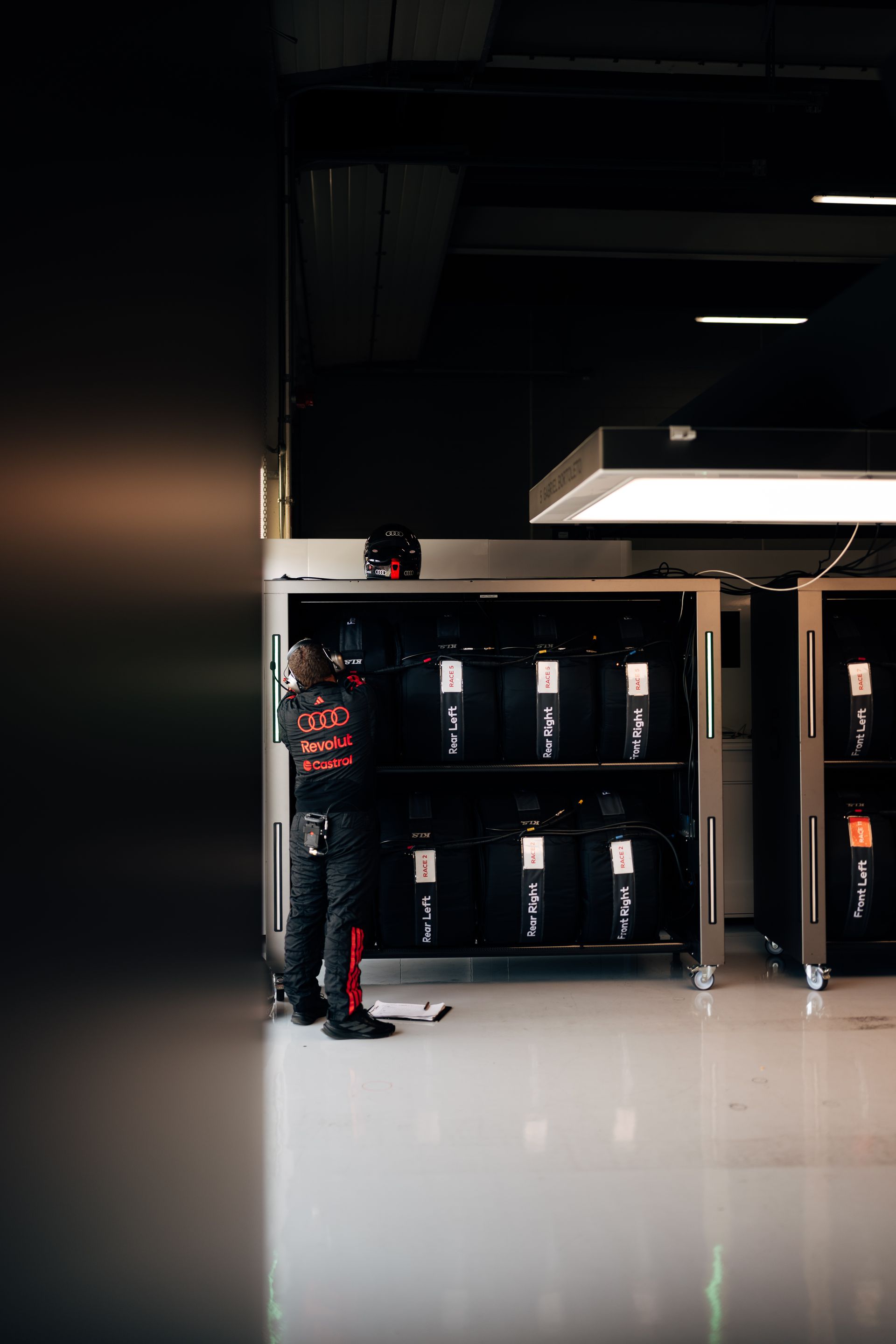 An Audi Revolut F1® Team crew member organises tyre sets inside the garage, preparing equipment for the race.