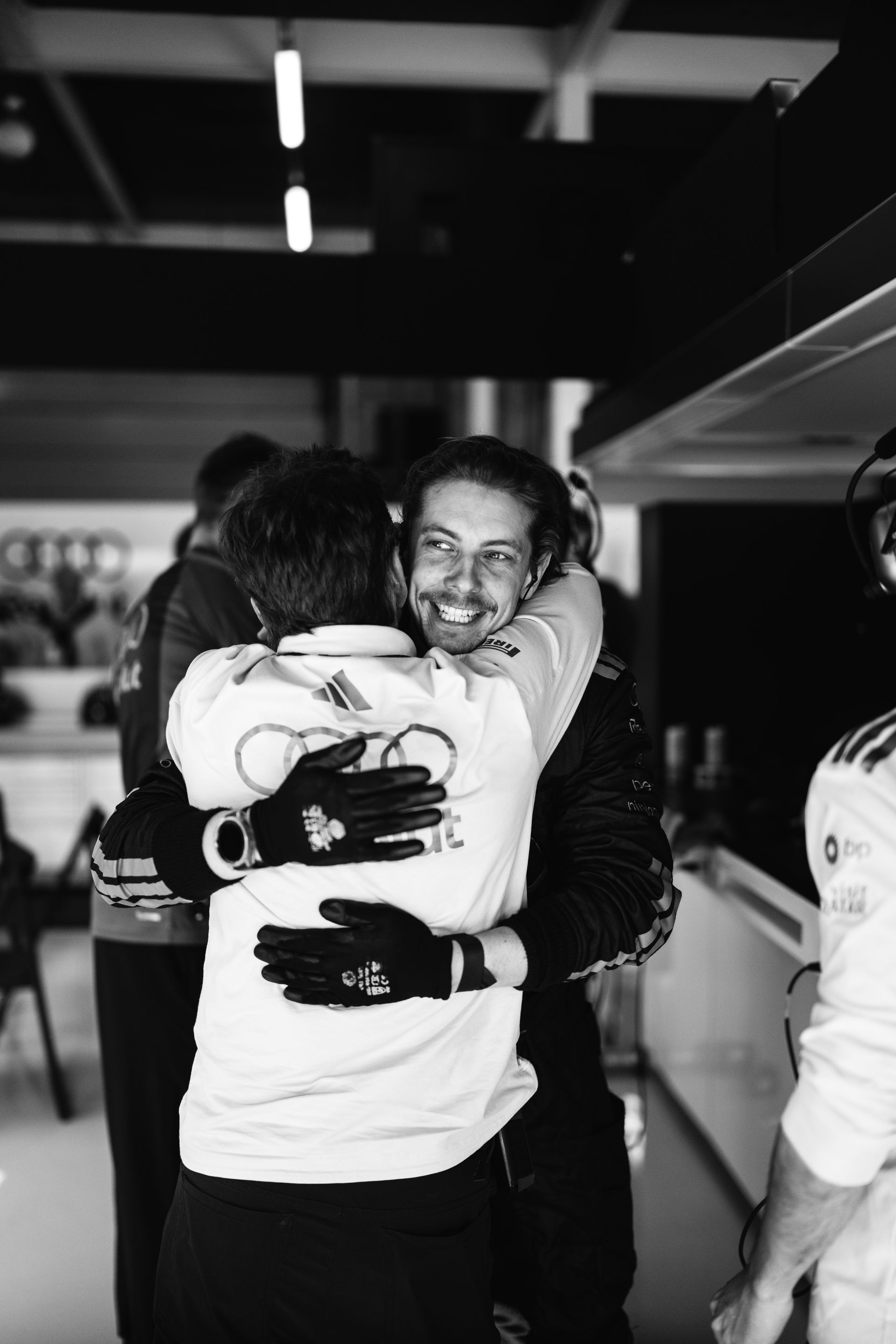 Audi Revolut F1® Team crew members embrace in the garage after the race, sharing a moment of relief and team spirit.