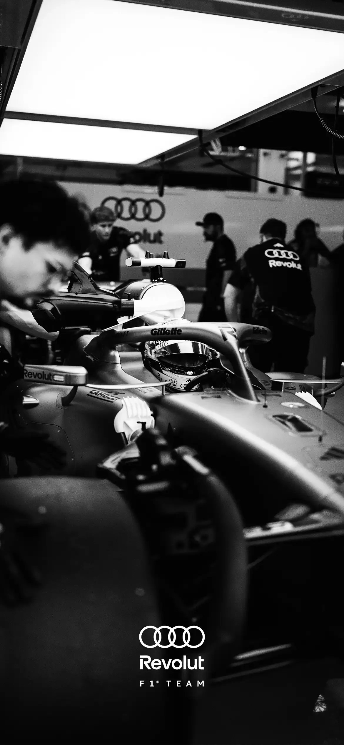 Sideview close up of the AUDI REVOLUT F1® TEAM car inside the garage, crew engineer leading the way next to the car, black and white photography