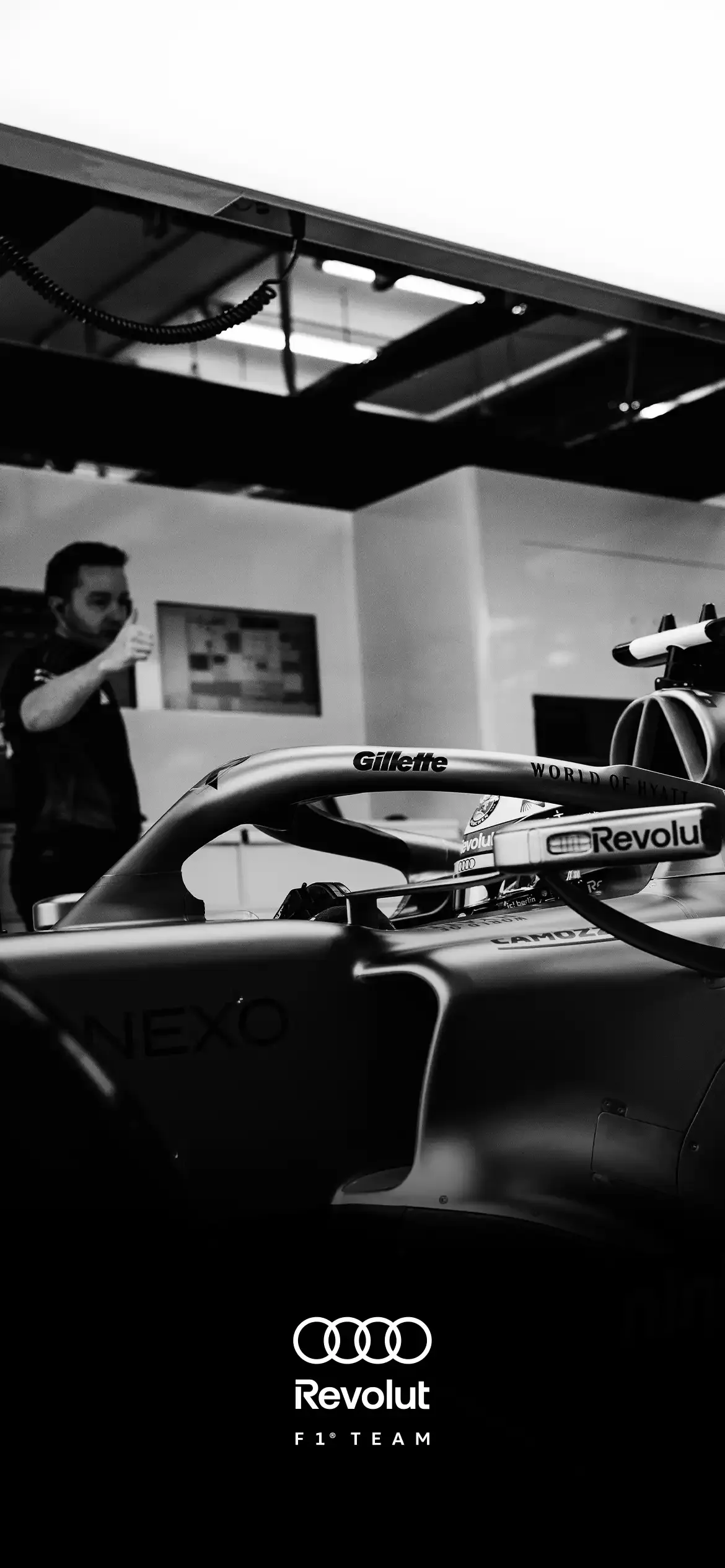Sideview close up of the AUDI REVOLUT F1® TEAM car inside the garage, crew engineer leading the way next to the car, black and white photography