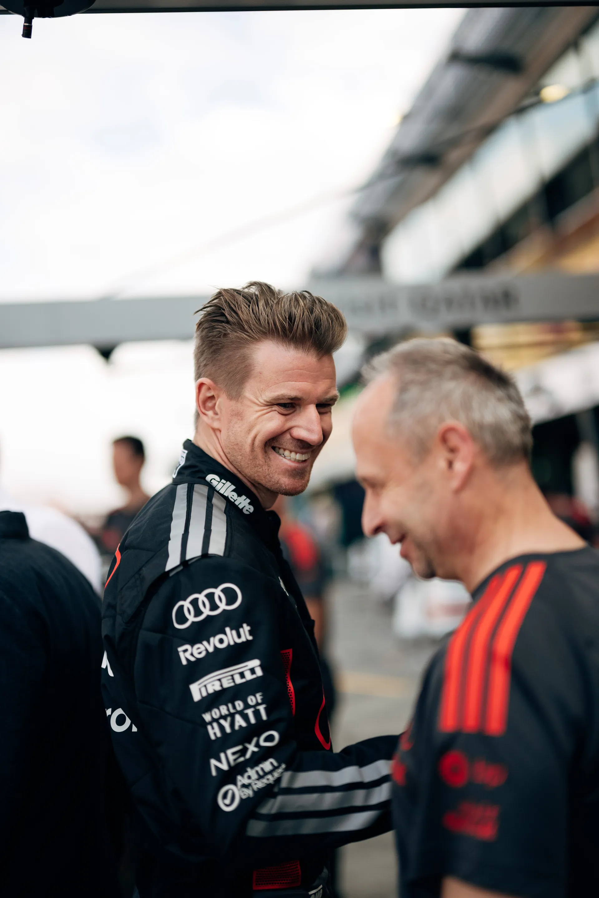 Audi Revolut F1® Team driver Nico Hulkenberg smiles while speaking with a team member in the Melbourne pit lane.