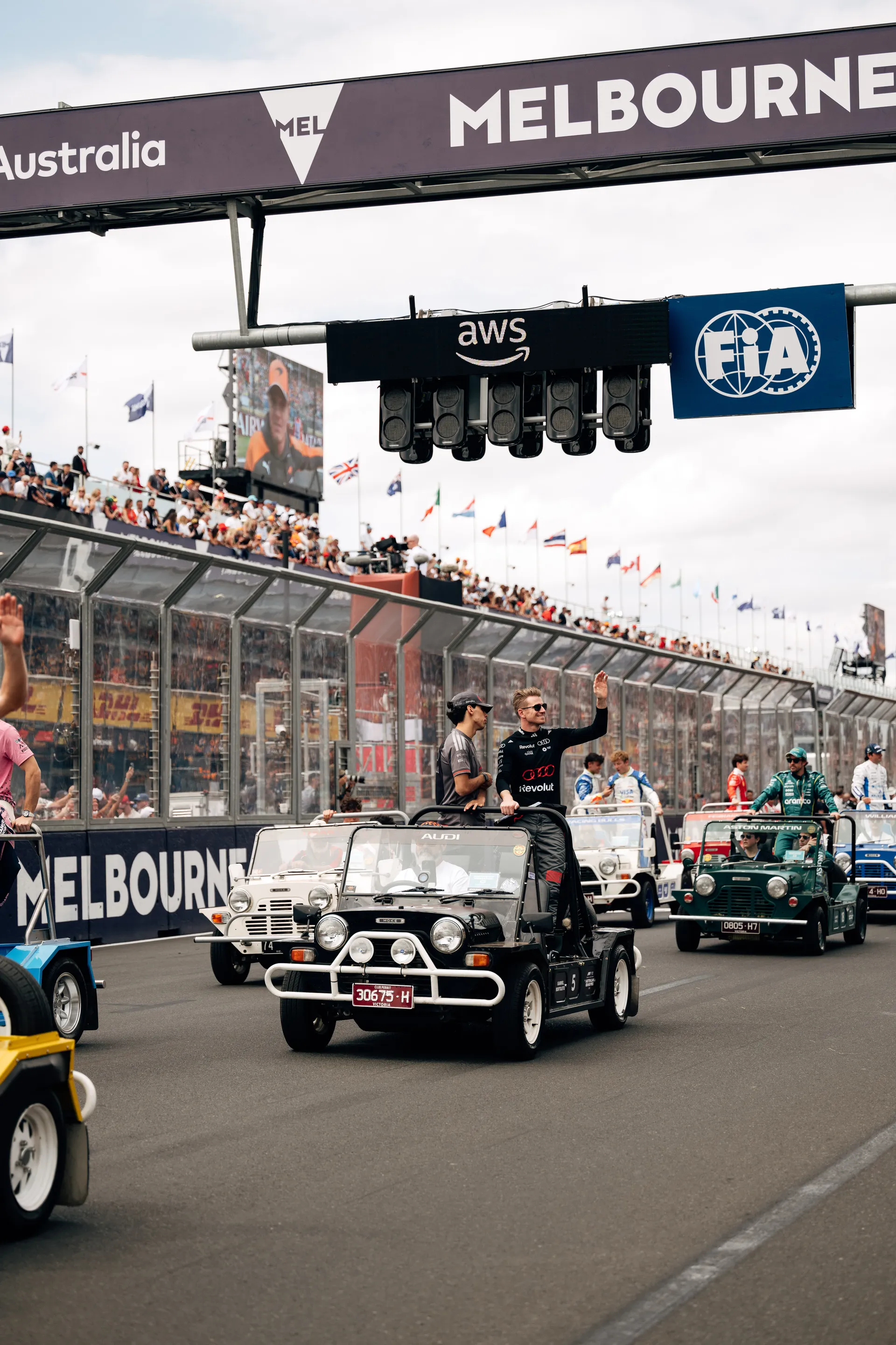 Audi Revolut F1® Team drivers Nico Hulkenberg and Gabriel Bortoleto ride in a parade vehicle and wave to fans on the Melbourne start finish straight.
