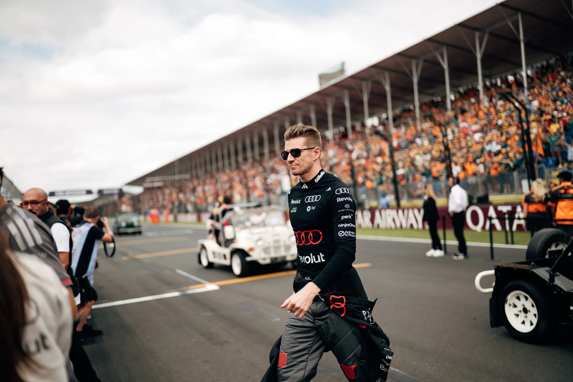 Audi Revolut F1® Team driver  Nico Hulkenberg walks through the grid surrounded by marshals, team members, and spectators in Melbourne.