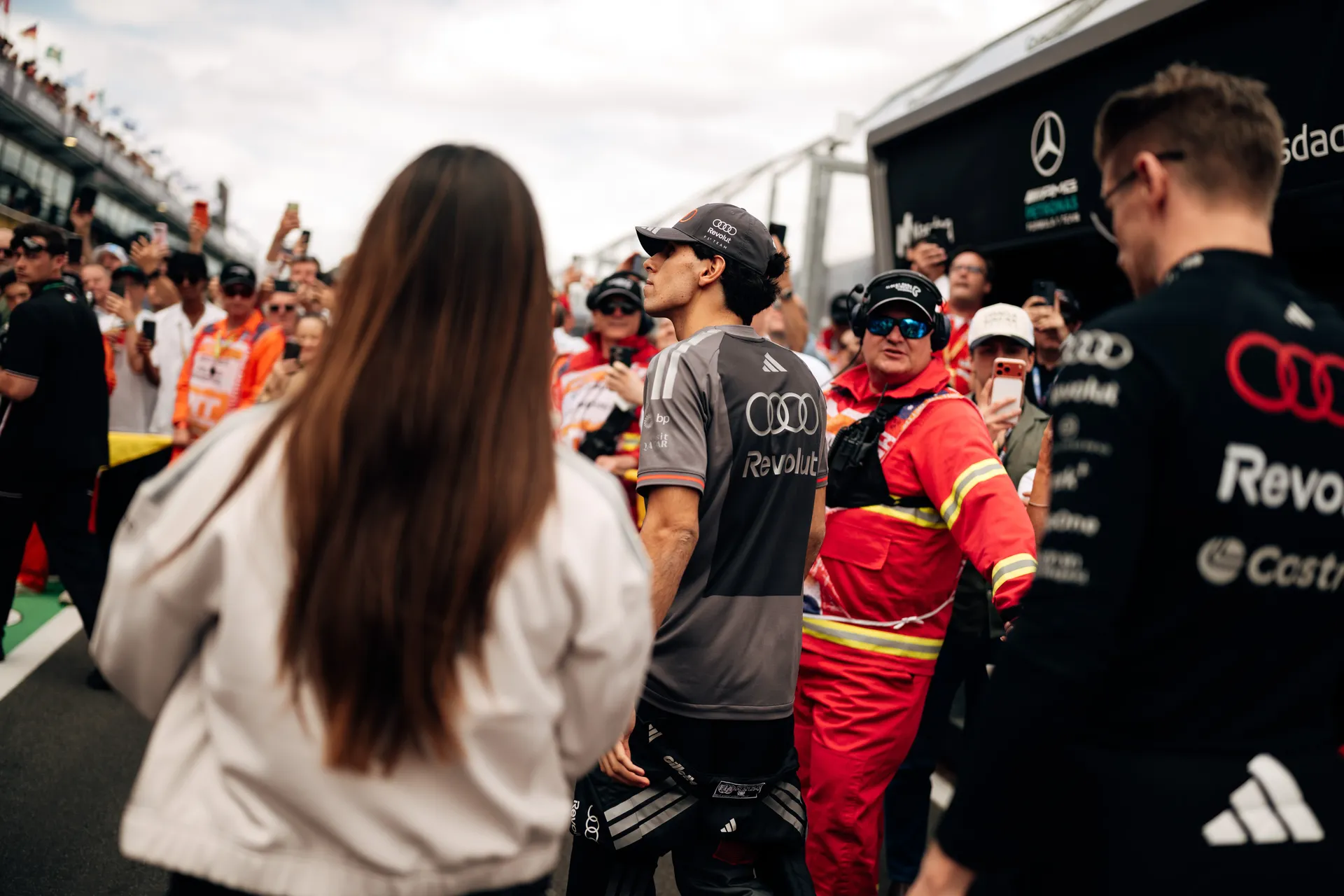 Audi Revolut F1® Team driver Gabriel Bortoleto walks through the grid surrounded by marshals, team members, and spectators in Melbourne.