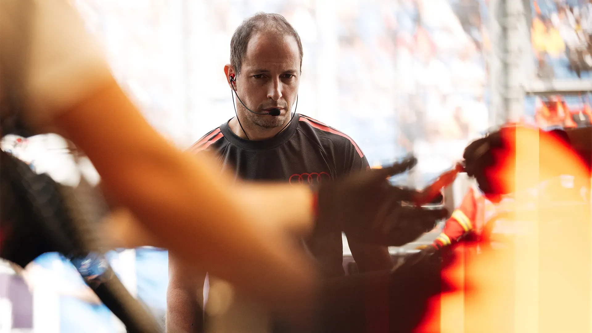 A Mechanic is in front of the car and the pit crew is setting up the car