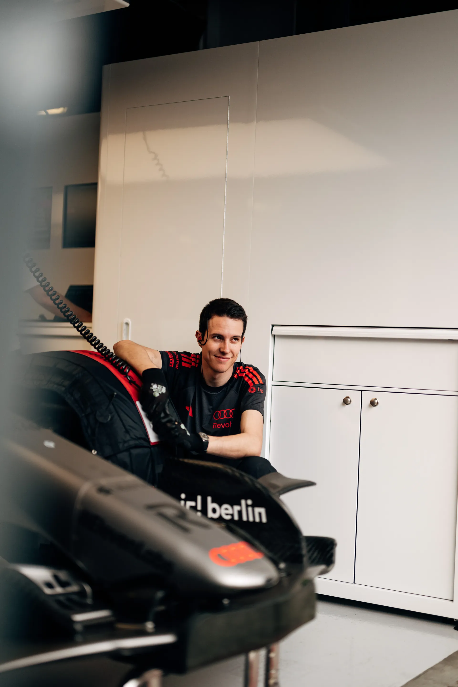 Audi Revolut F1® Team crew member sits beside the car and tire stack inside the garage during a quiet moment in qualifying.