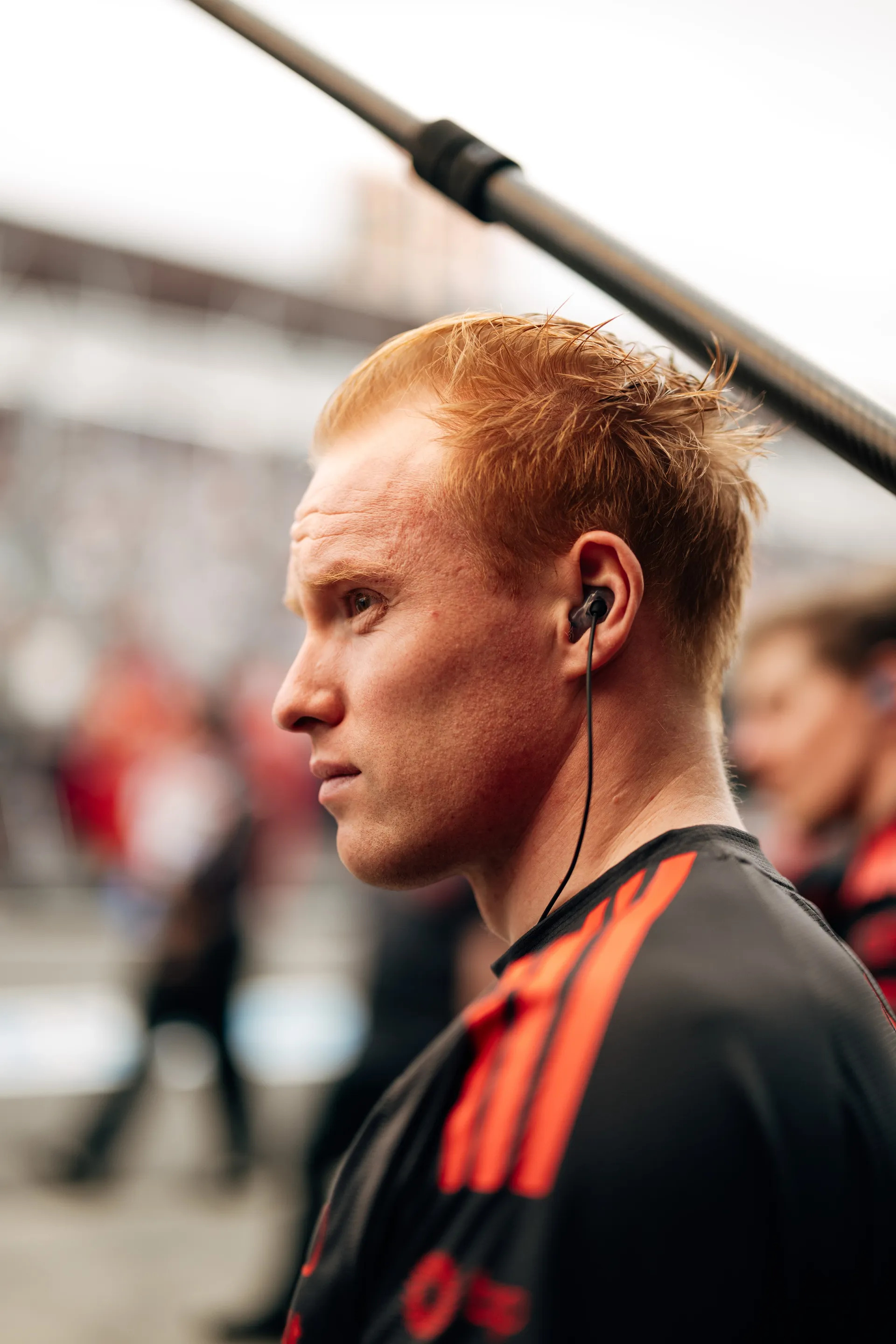 Close profile portrait of an Audi Revolut F1® Team crew member wearing an earpiece and watching the pit lane during qualifying.