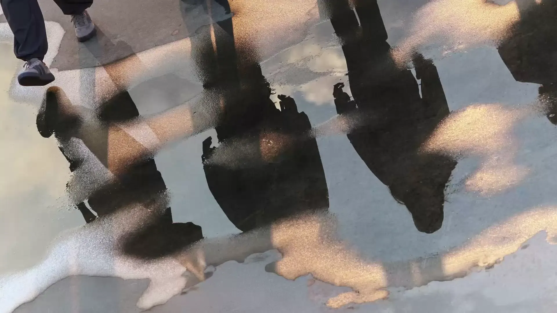 Asphalt street filled with rain reflecting the silhouette of people