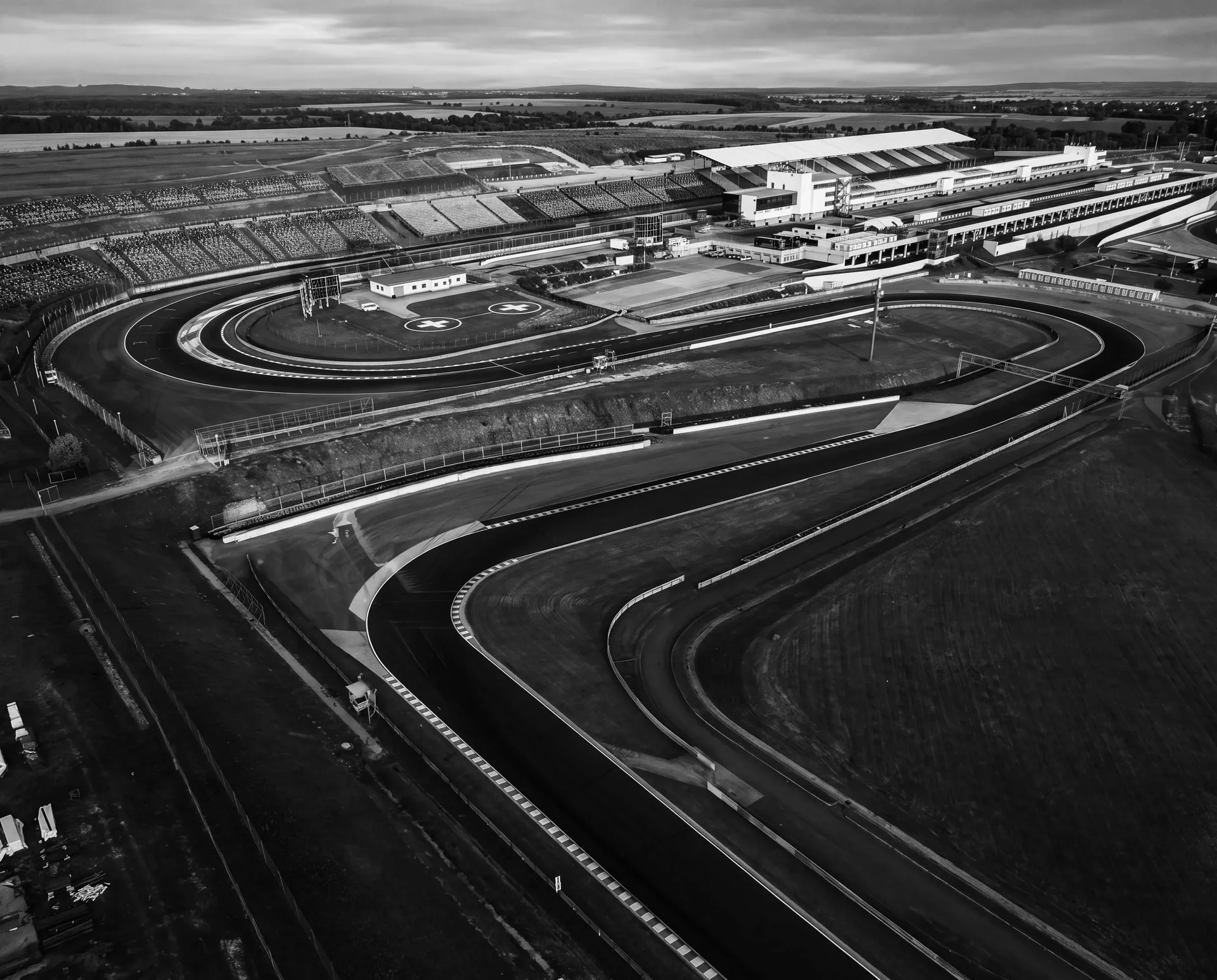 Black-and-white aerial of the Hungaroring pit straight, paddock and infield hairpin before the Audi Revolut F1® Team Hungarian GP