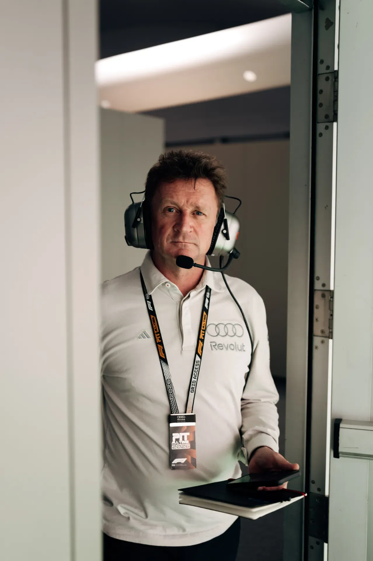 Allan McNish of the Audi Revolut F1® Team wearing a headset and Grid Access lanyard in a doorway in Austin