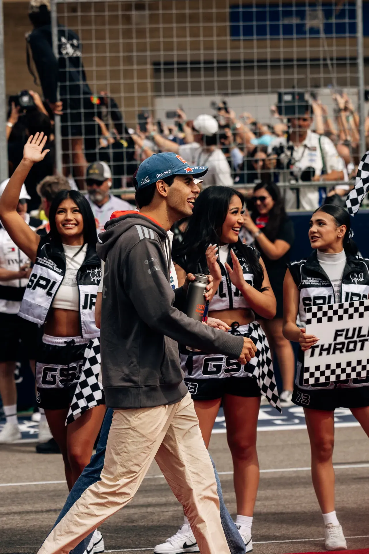 Gabriel Bortoleto of the Audi Revolut F1® Team in blue cap and grey hoodie walks past grid girls on the grid in Austin