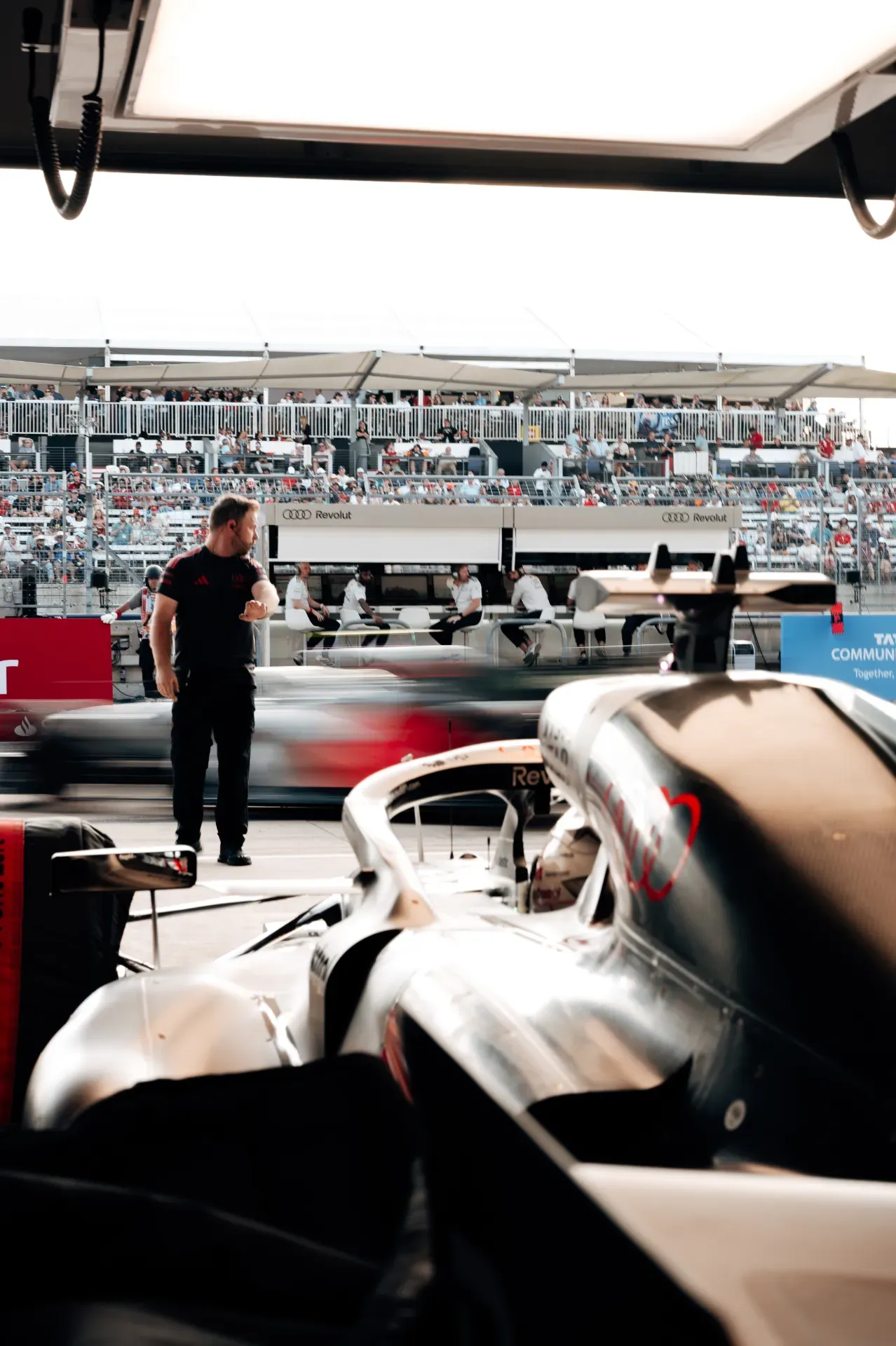Car of the Audi Revolut F1® Team in the garage with a mechanic and a passing car in the pit lane in Austin
