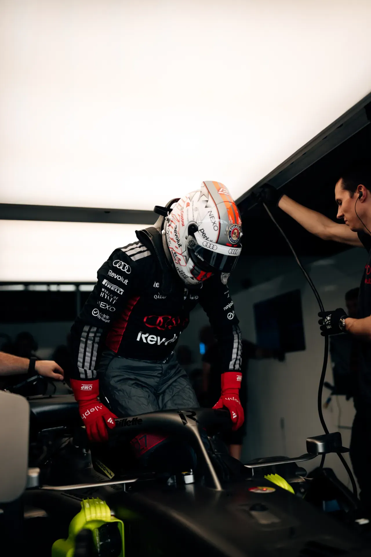 Nico Hulkenberg of the Audi Revolut F1® Team climbs into the car in the garage in Austin as a mechanic assists