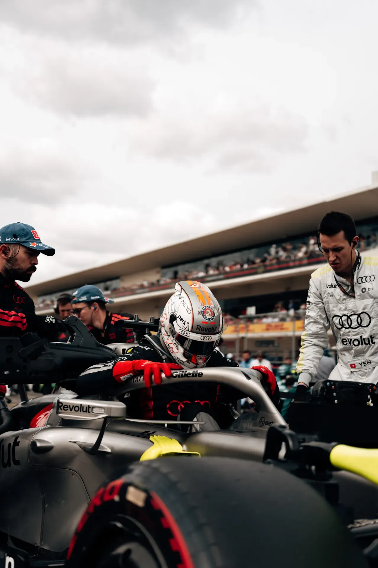 Nico Hulkenberg of the Audi Revolut F1® Team in a white helmet and red gloves climbs into the car as a mechanic watches in Austin