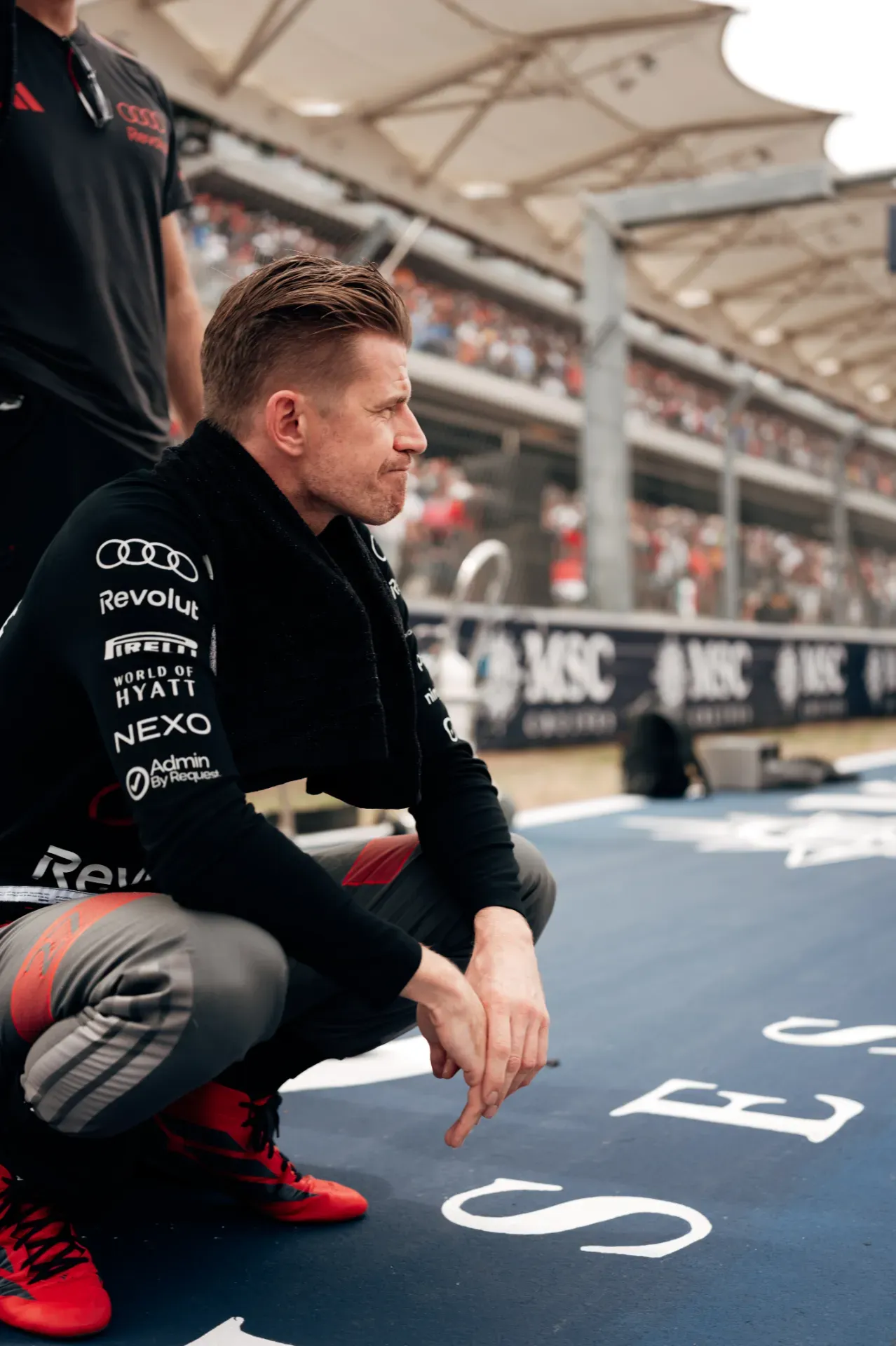 Nico Hulkenberg of the Audi Revolut F1® Team crouching on the grid in Austin with a black towel around the neck