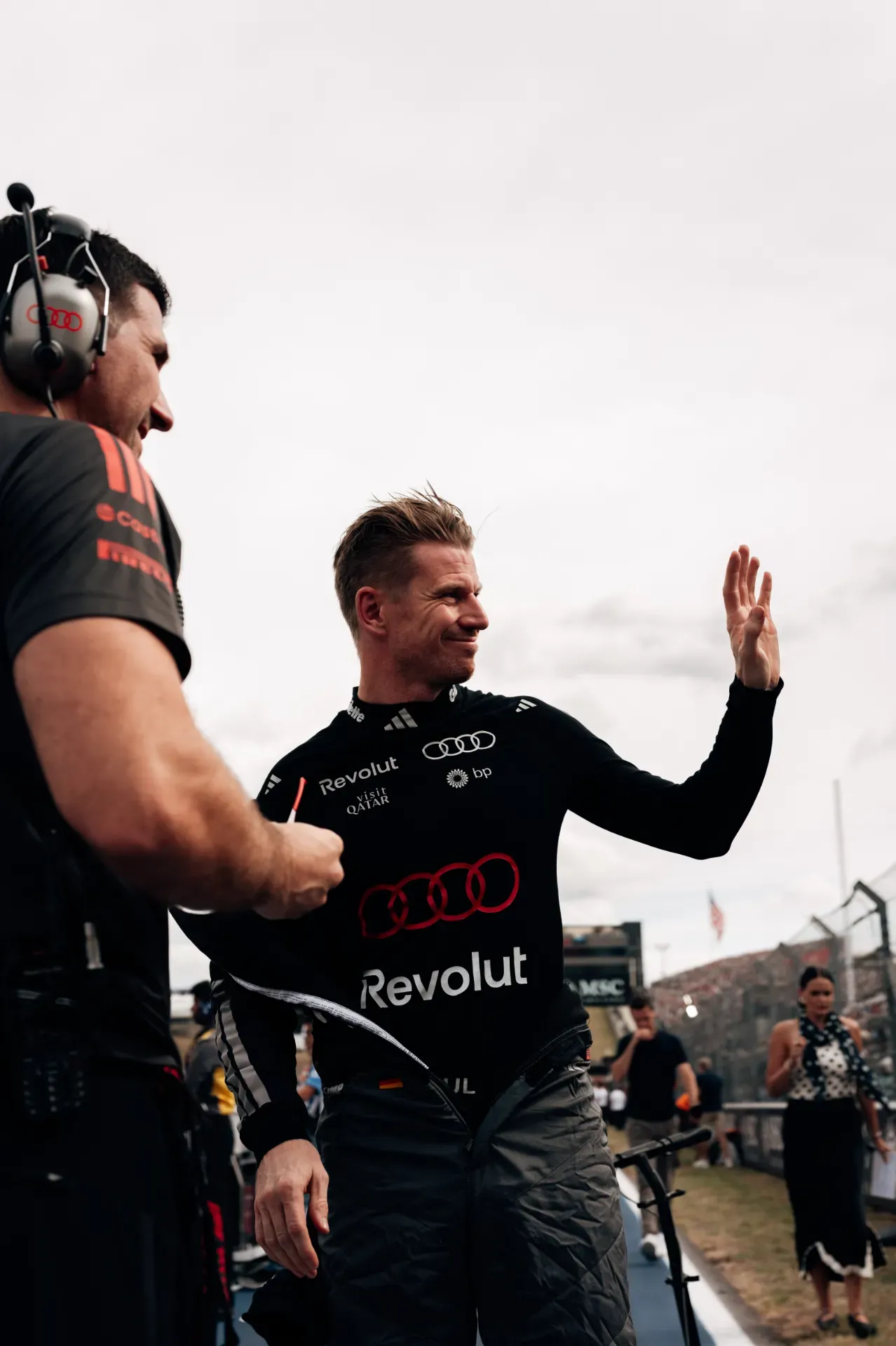 Nico Hulkenberg of the Audi Revolut F1® Team waves next to a mechanic with a headset in Austin