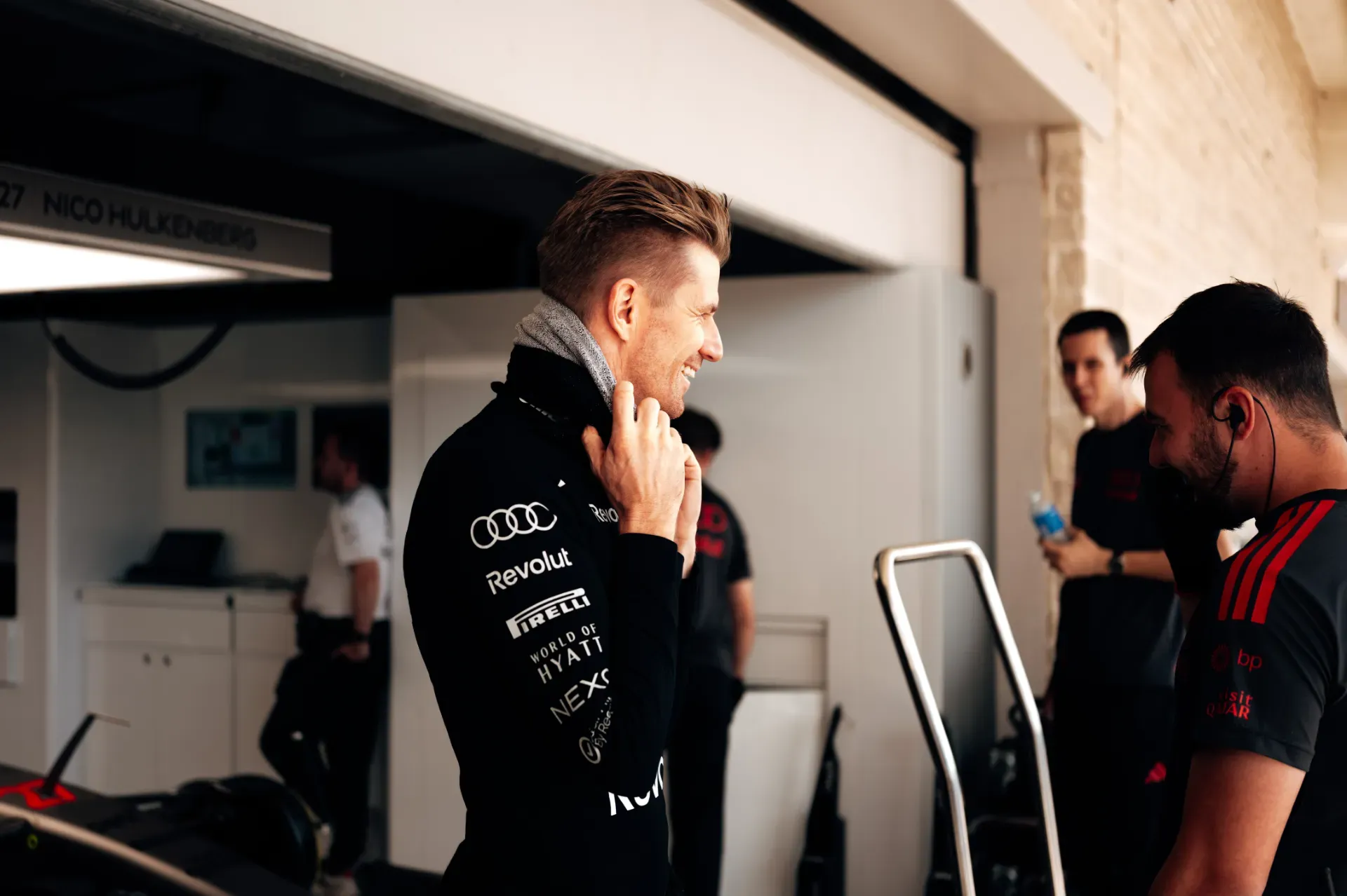Nico Hulkenberg of the Audi Revolut F1® Team smiling in the garage in Austin with two team members beside him