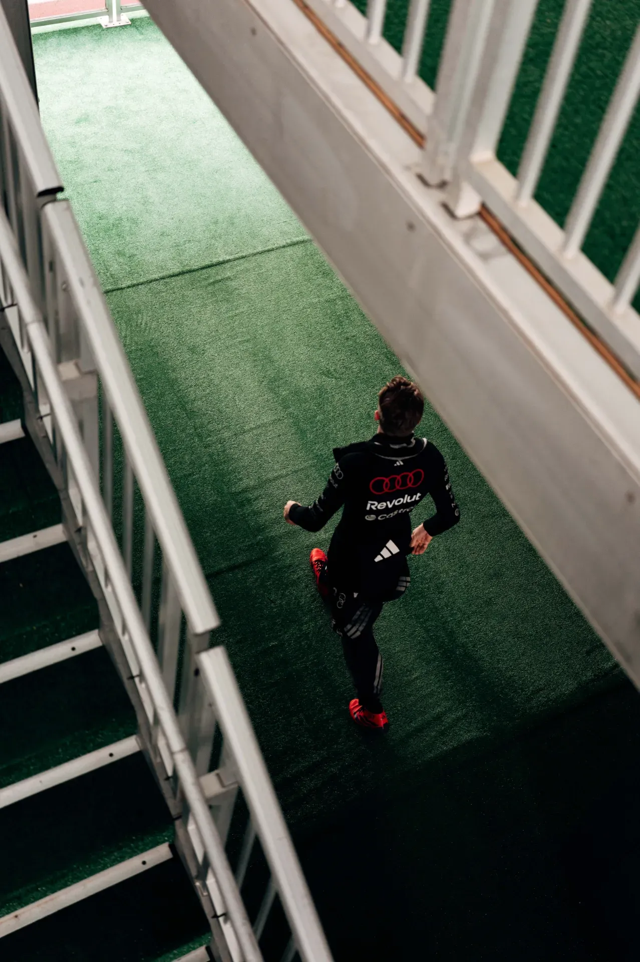 Nico Hulkenberg of the Audi Revolut F1® Team in black team kit and red shoes walking along a green walkway in Austin