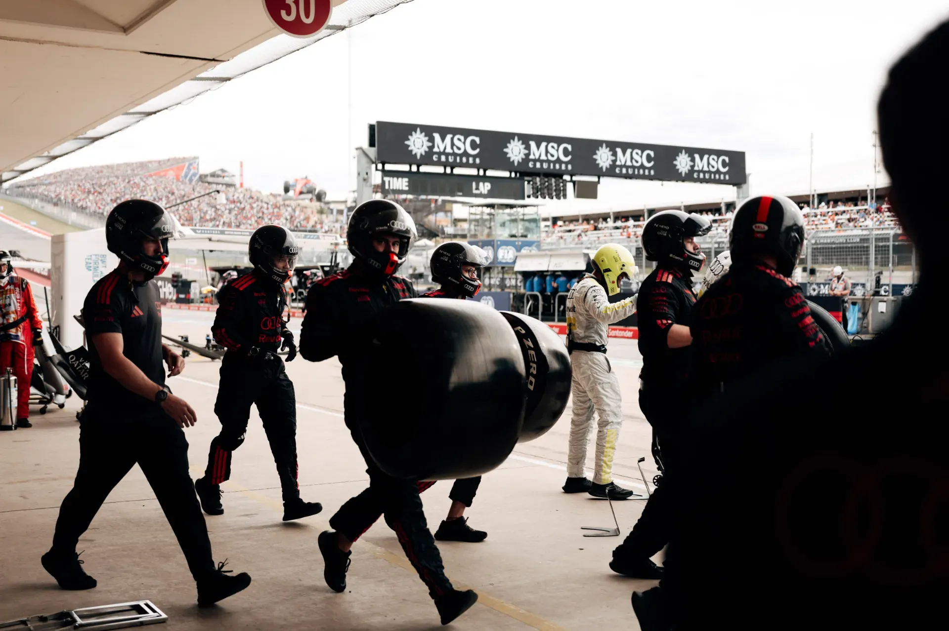 Mechanics of the Audi Revolut F1® Team carrying tyres through the pit lane in Austin