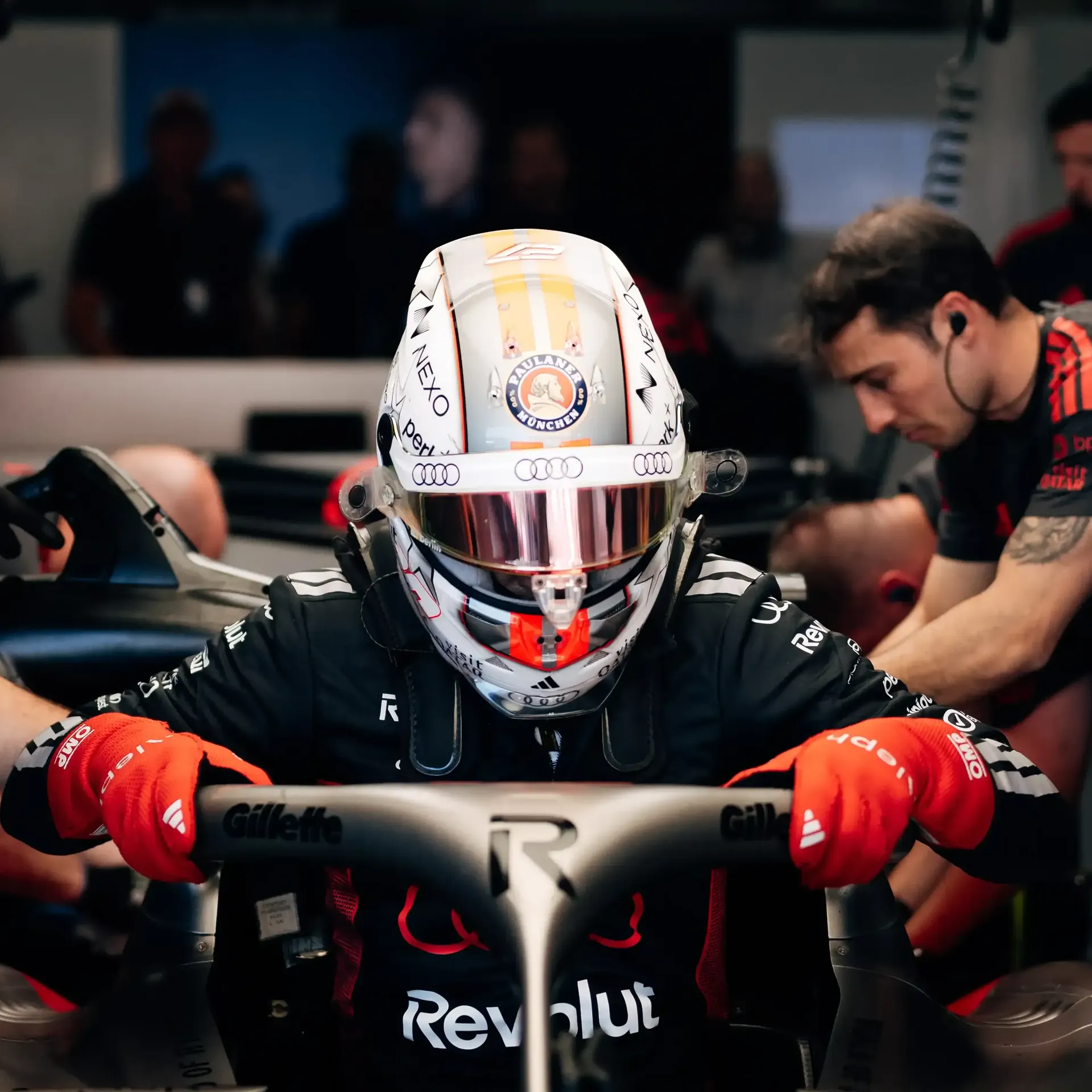 Nico Hulkneberg driver at the Audi Revolut F1® Team inside the garage surrounded by team mechanics jumping inot the cockpit of the Audi R26