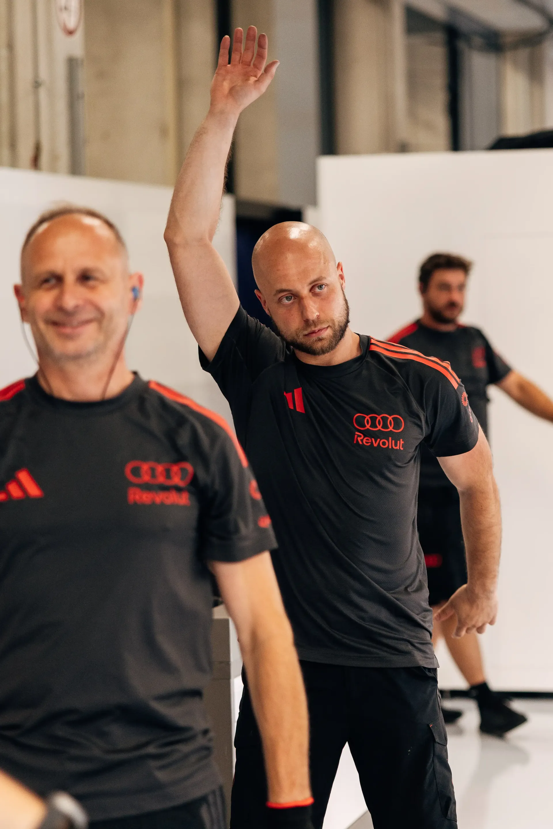 An Audi Revolut F1® Team mechanics stretch out inside the garage ahead of the Formula 1® Austrian Grand Prix at the Red Bull Ring.