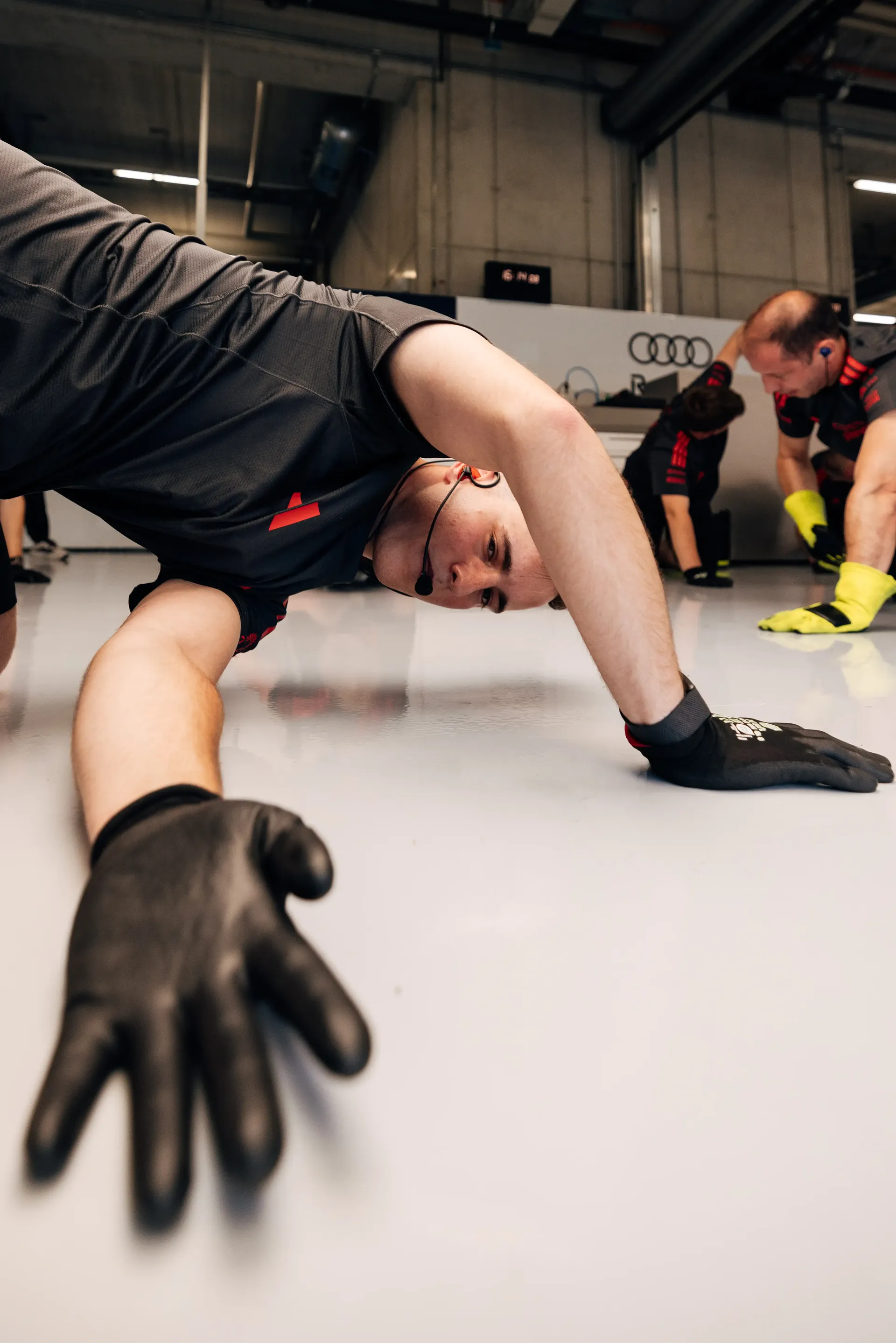 An Audi Revolut F1® Team mechanics stretch out on the floor inside the garage ahead of the Formula 1® Austrian Grand Prix at the Red Bull Ring.