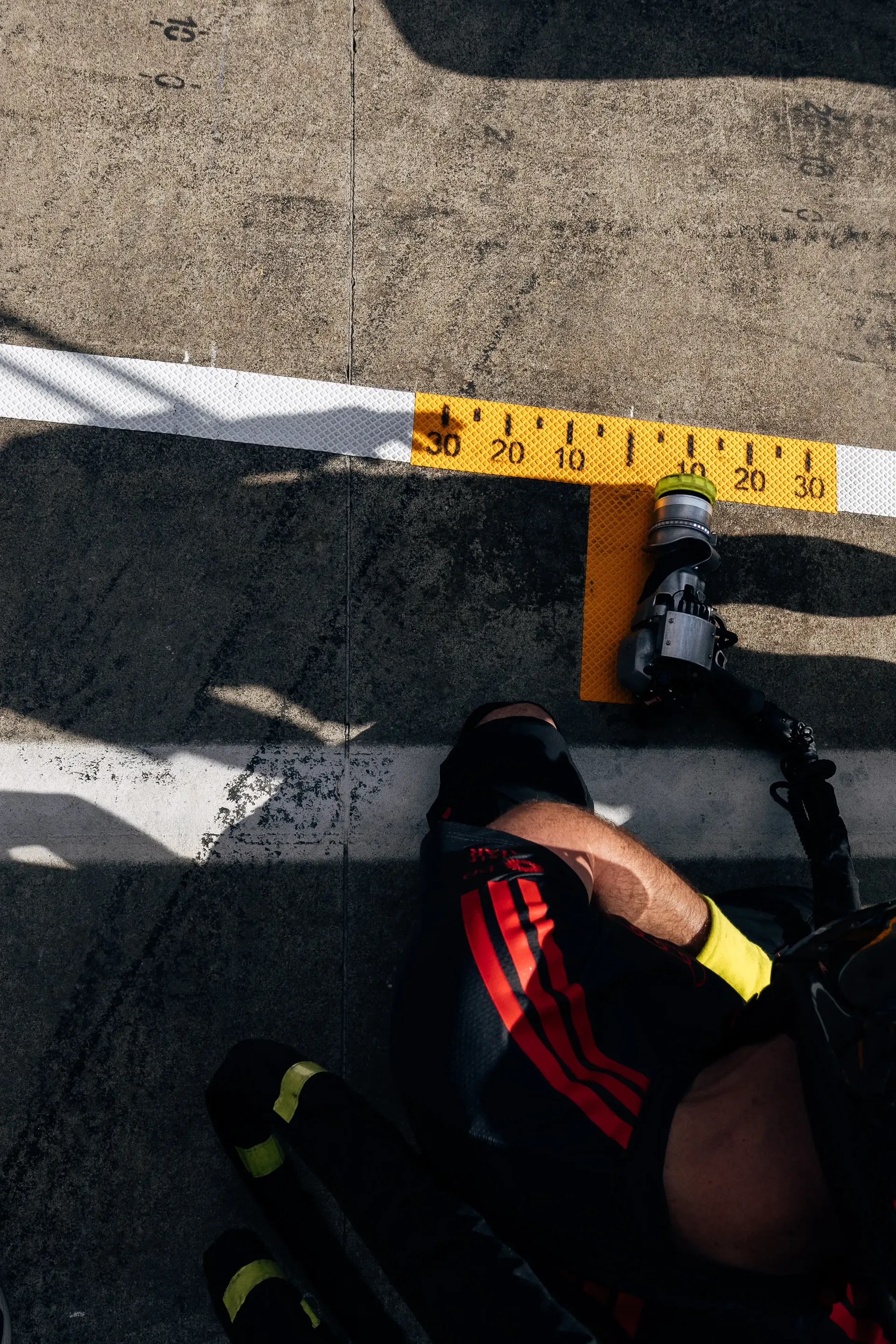 An Audi Revolut F1® Team pit stop crew member measures pit box positioning during pit stop practice ahead of the Formula 1® Austrian Grand Prix at the Red Bull Ring.