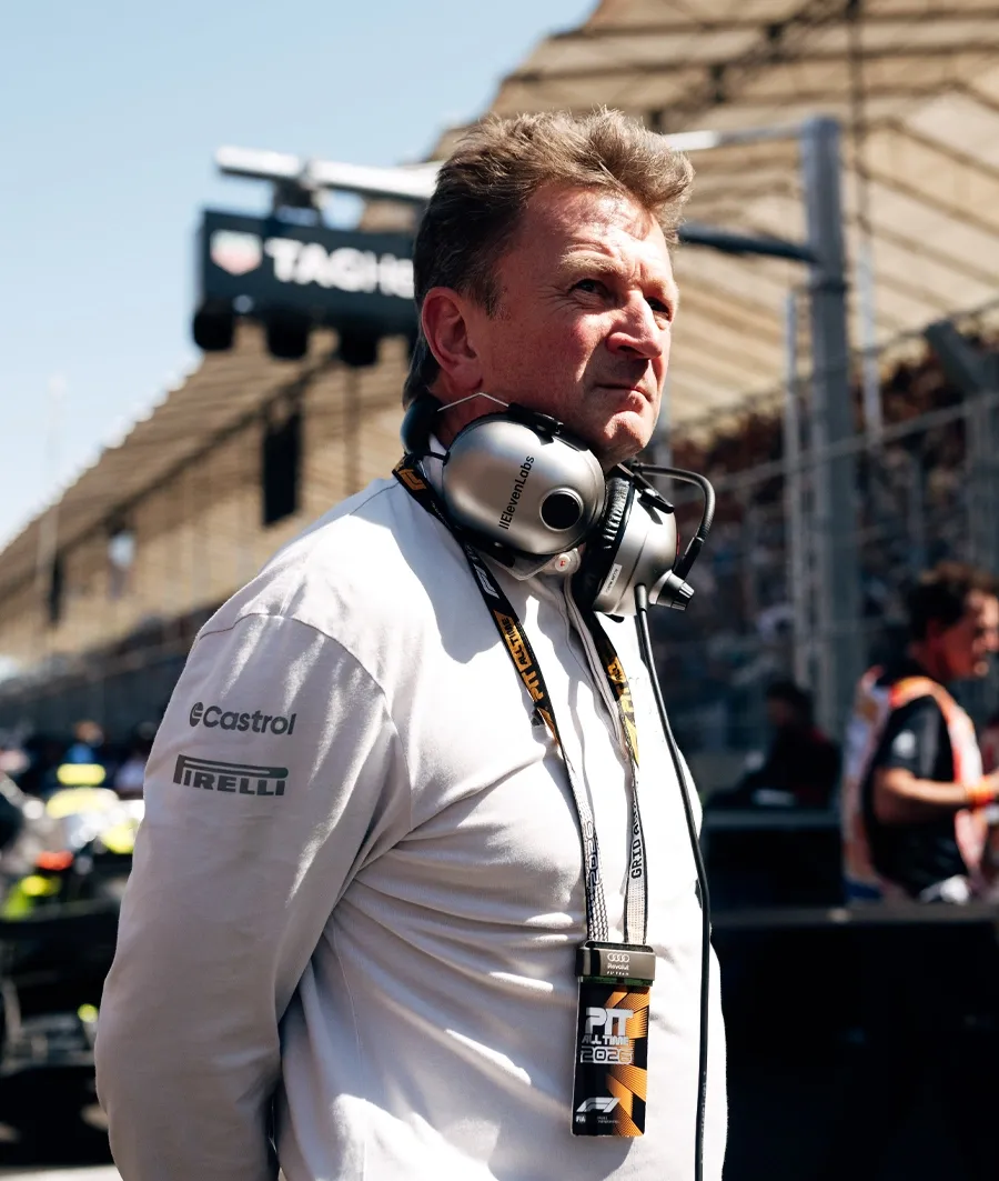 Audi Revolut F1® Team raceing director Allan McNish stands beside the garage wearing headphones