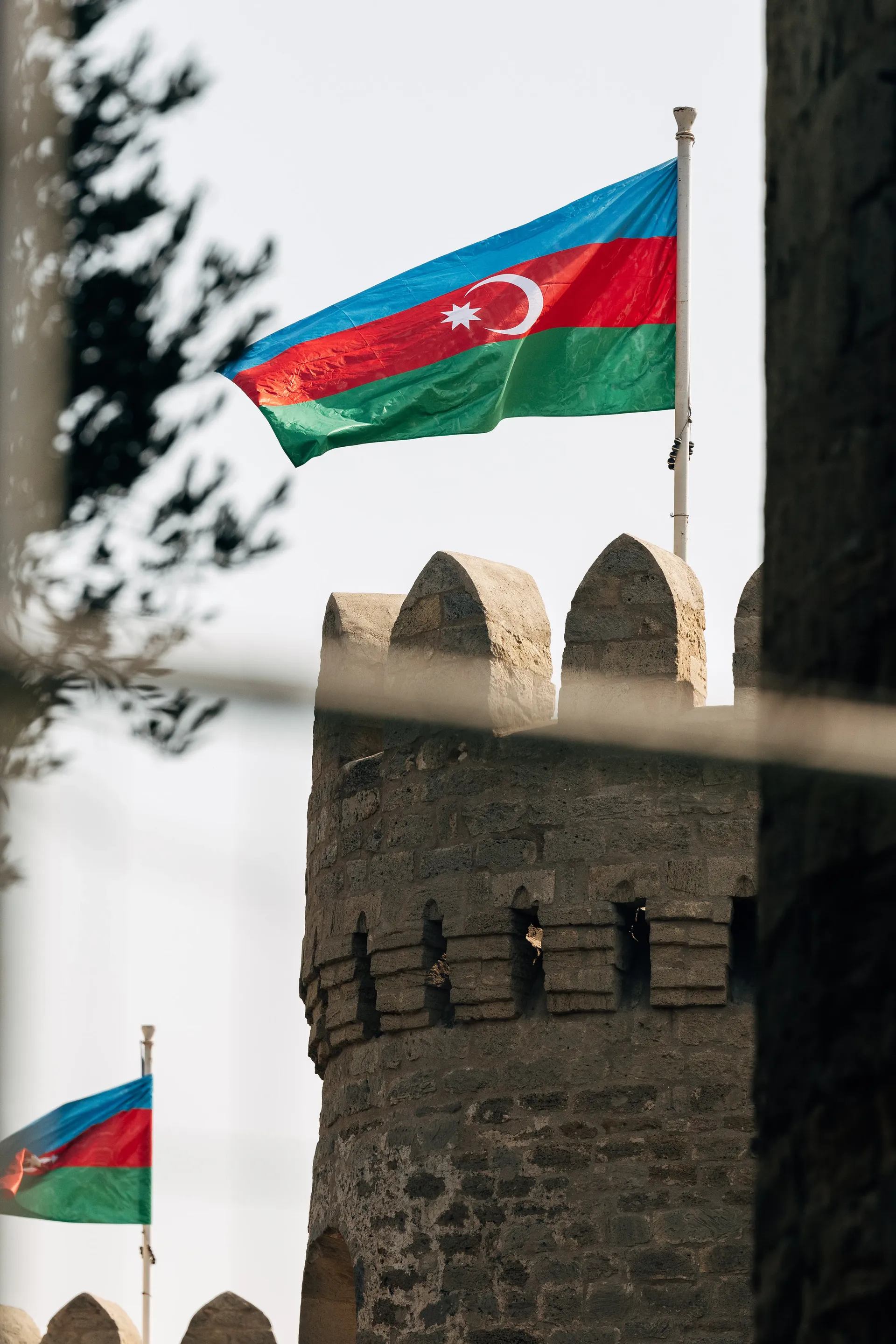 Azerbaijan flags above a historic stone tower in Baku