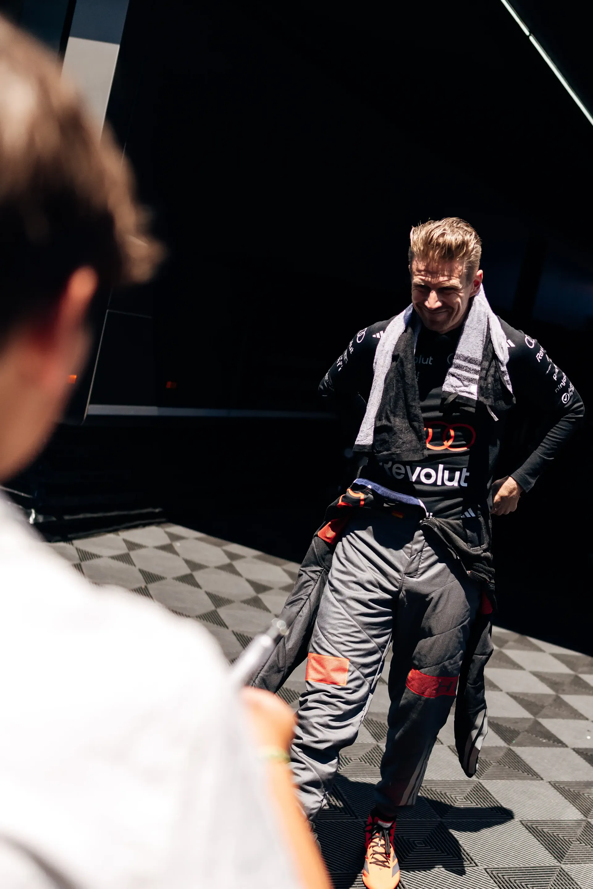 Nico Hulkenberg walks through the Audi Revolut F1® Team garage in his race suit during FP3 at the Austrian Grand Prix in Spielberg, Austria.