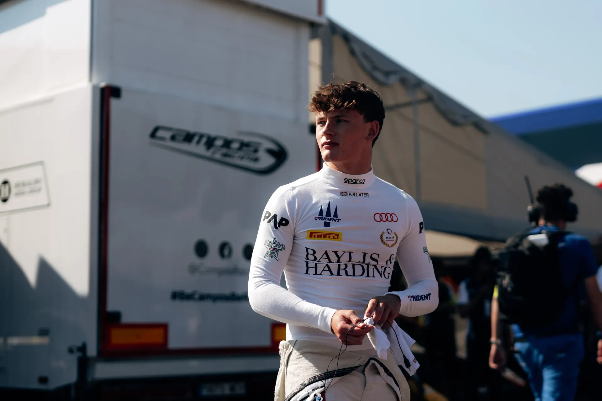 Freddie Slater walks through the Spielberg paddock in his race suit ahead of the FIA Formula 3 race.