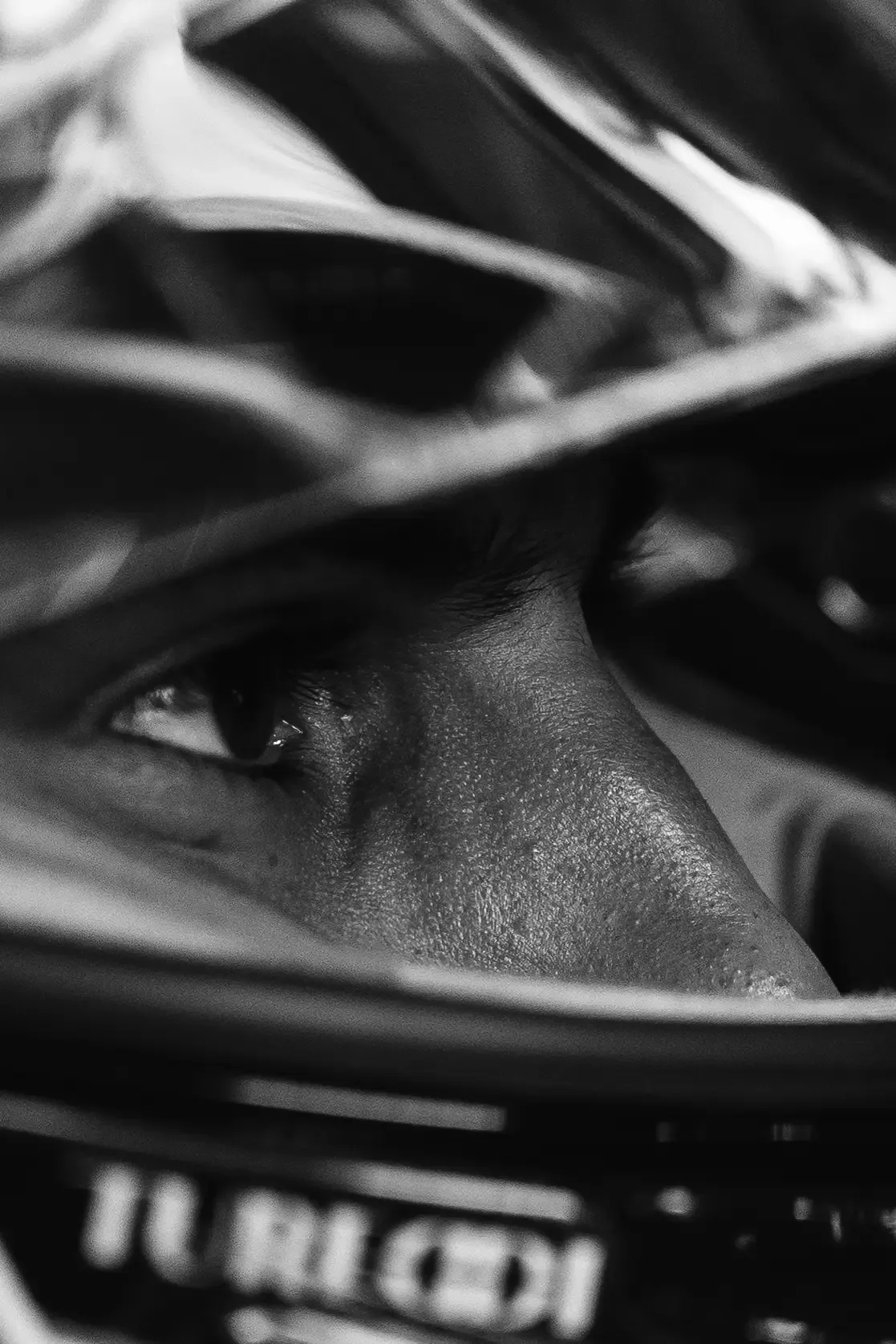 Black-and-white close-up of an Audi Revolut F1® Team driver Gabriel Bortoleto focused eyes behind the helmet visor in the cockpit.