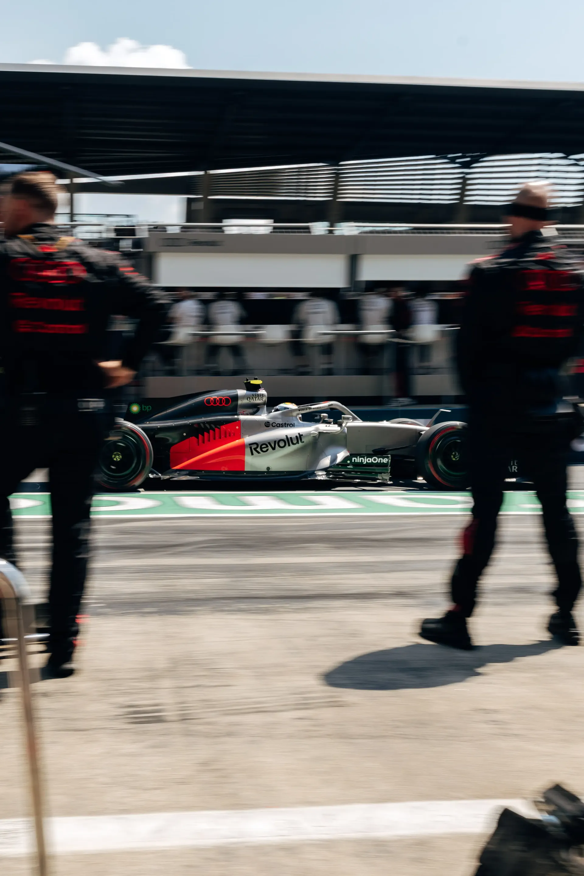 The Audi R26 waits in the pit lane as mechanics walk past before the race.