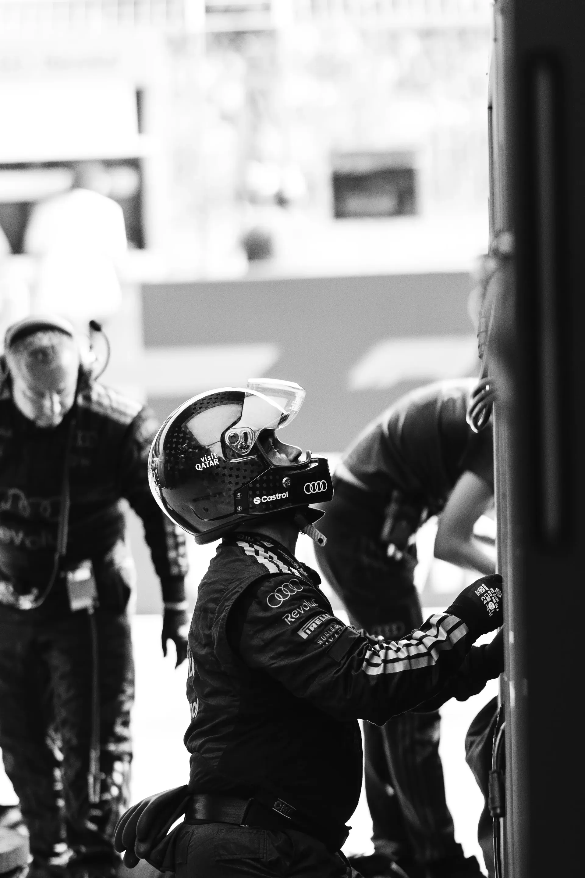 Black-and-white image of Audi Revolut F1® Team mechanics preparing equipment inside the garage.