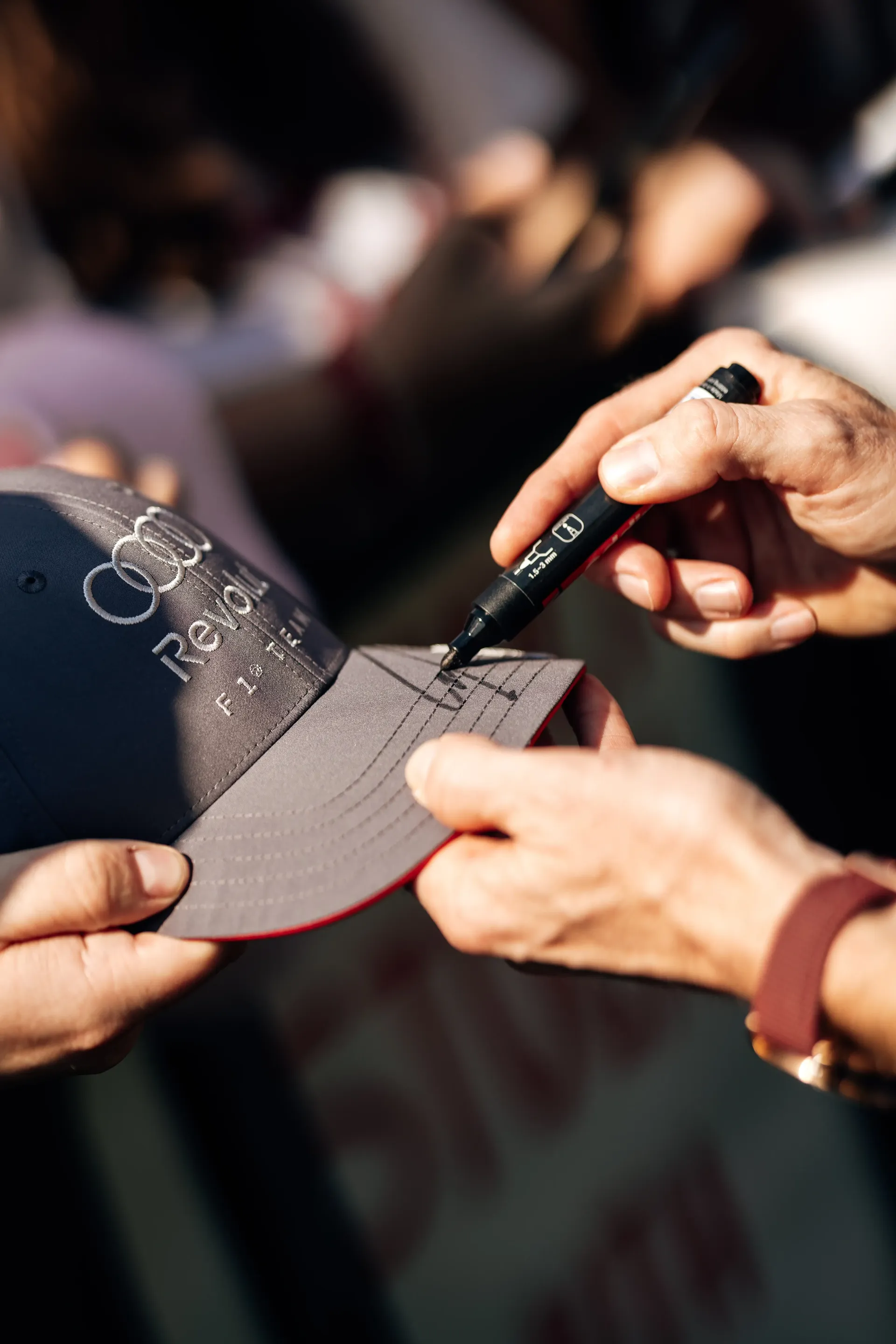 Close-up of Nico Hulkenberg signing an Audi Revolut F1® Team cap for a fan before the Formula 1® Austrian Grand Prix in Spielberg before the race.