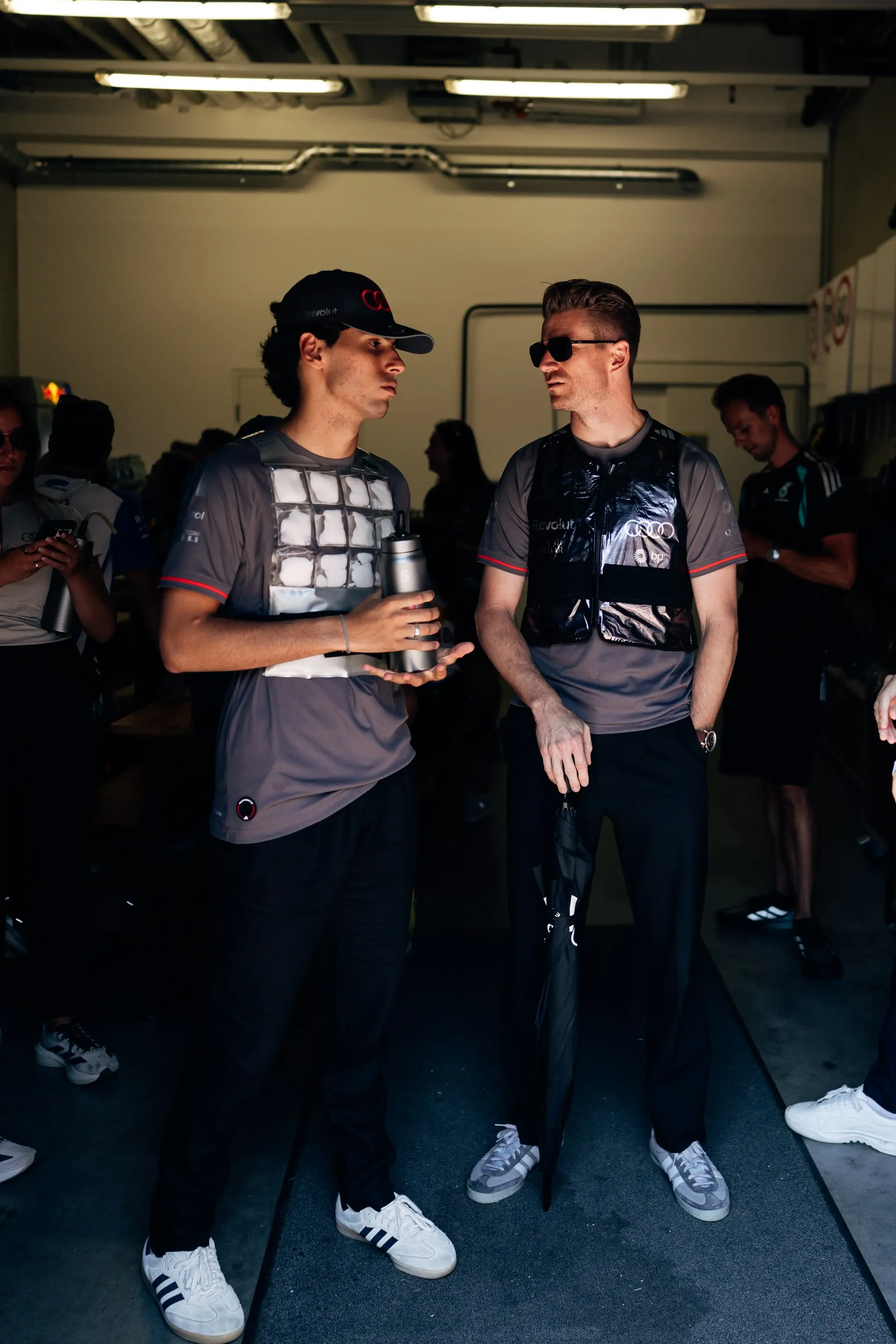 Nico Hulkenberg and Gabriel Bortoleto chat in the Audi Revolut F1® Team garage ahead of the Formula 1 Drivers' Parade before the Austrian Grand Prix in Spielberg.